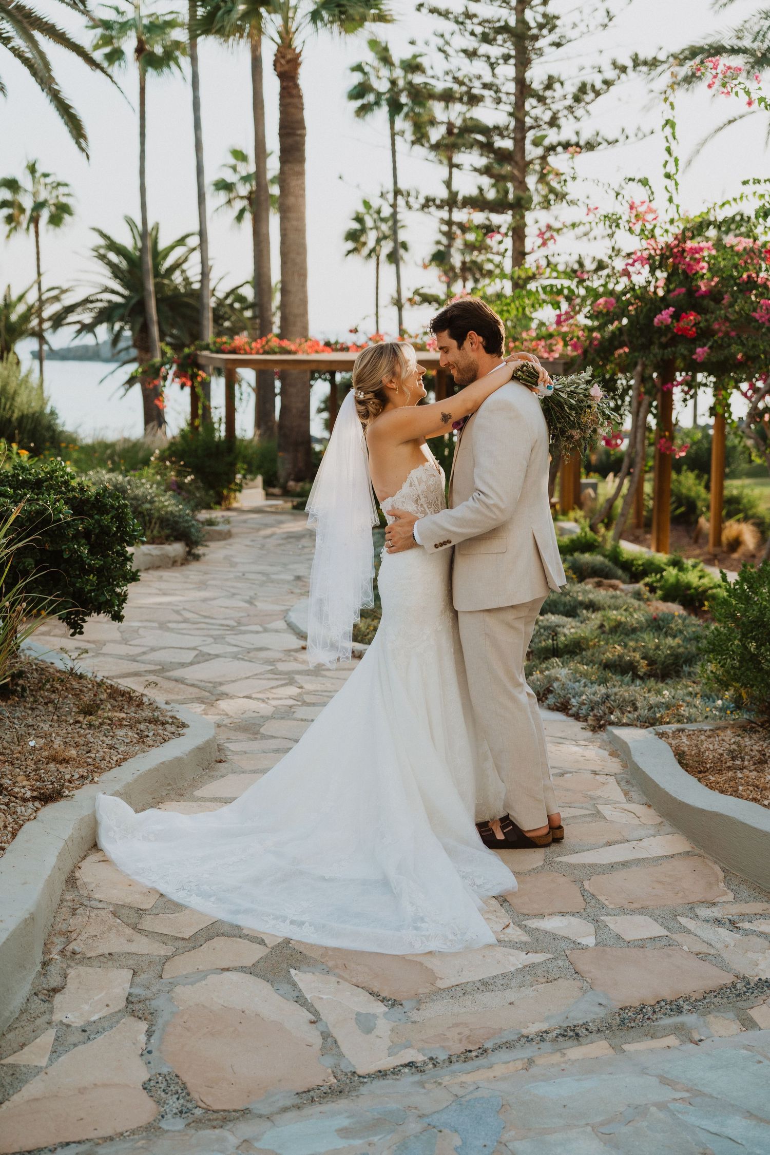 Wedding couple shares tender moments along a winding stone path with tropical garden backdrop.