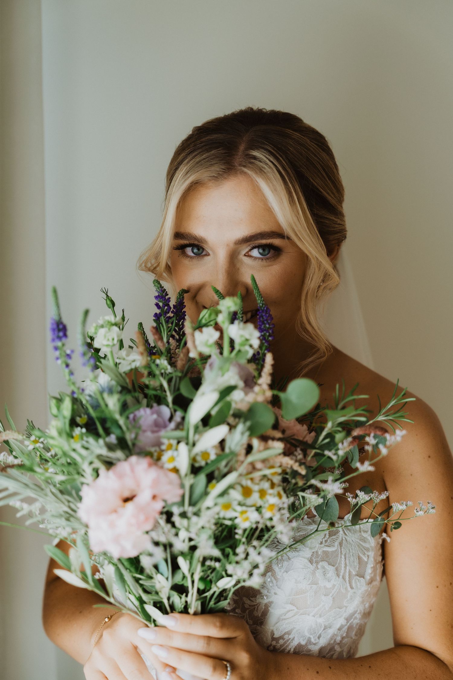 Elegant bridal bouquet featuring pink peonies, purple delphinium, and eucalyptus leaves.