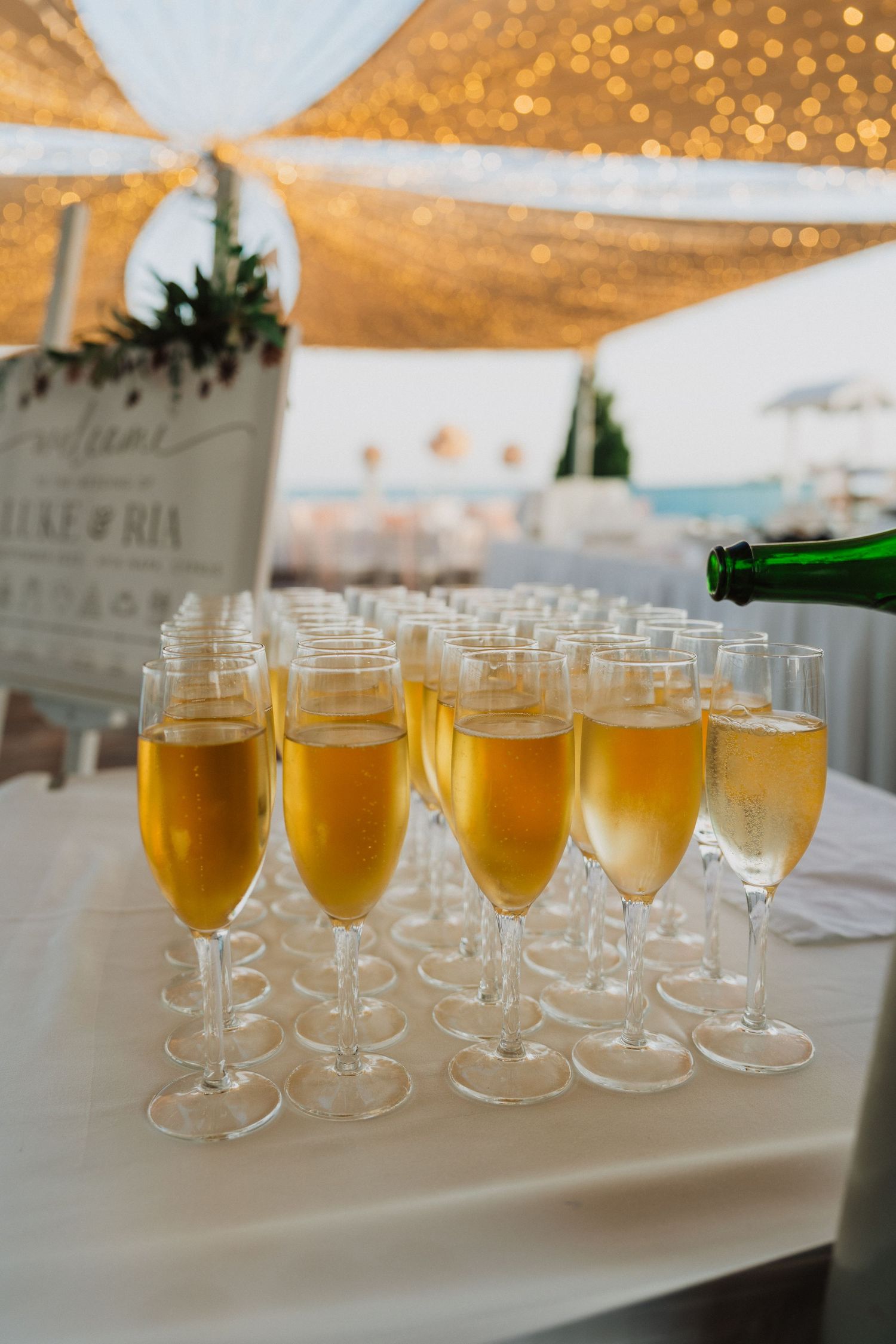 Champagne flutes filled with golden bubbly being served at an outdoor wedding reception.