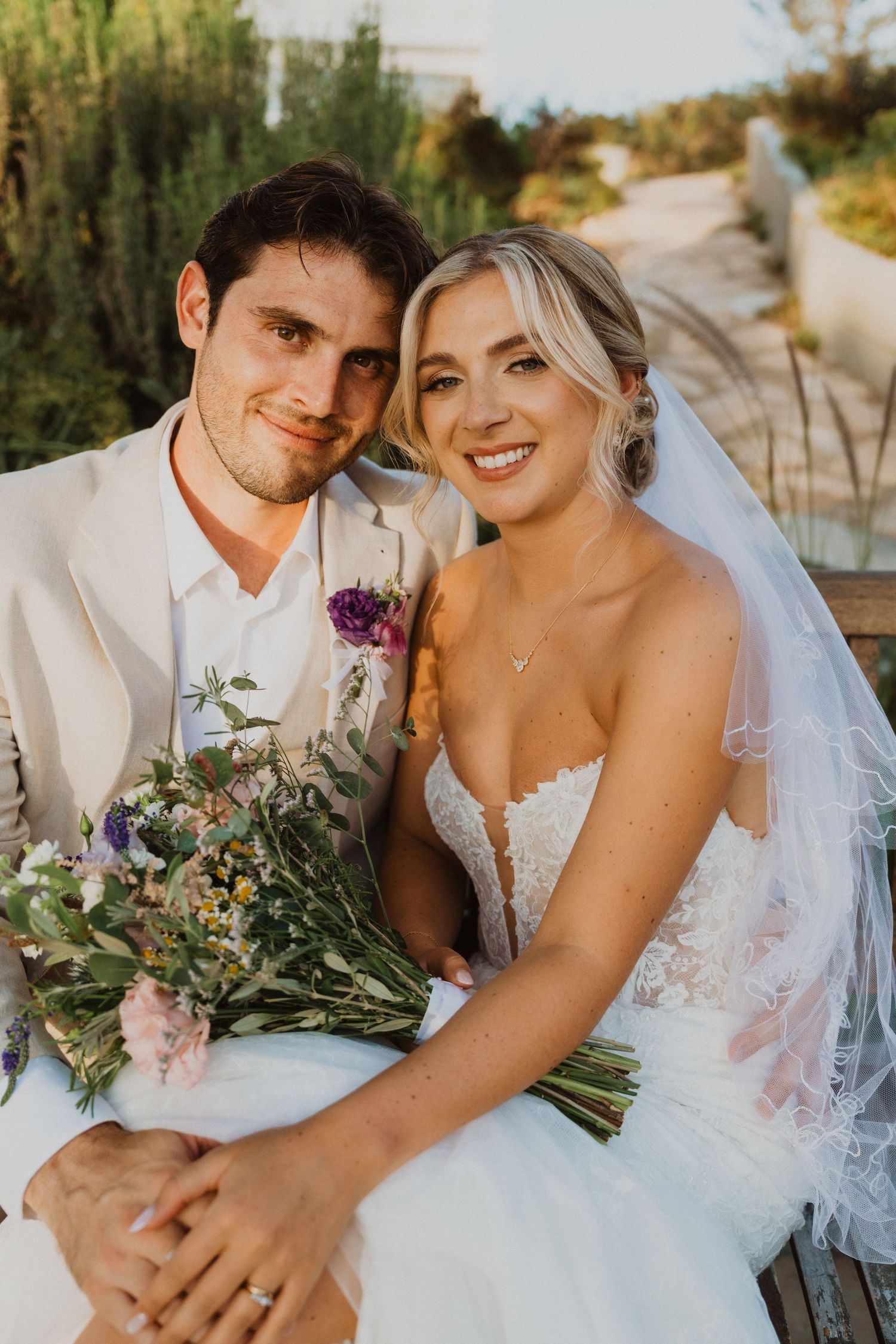 Intimate wedding portraits on a wooden bench with a colorful bouquet of flowers.