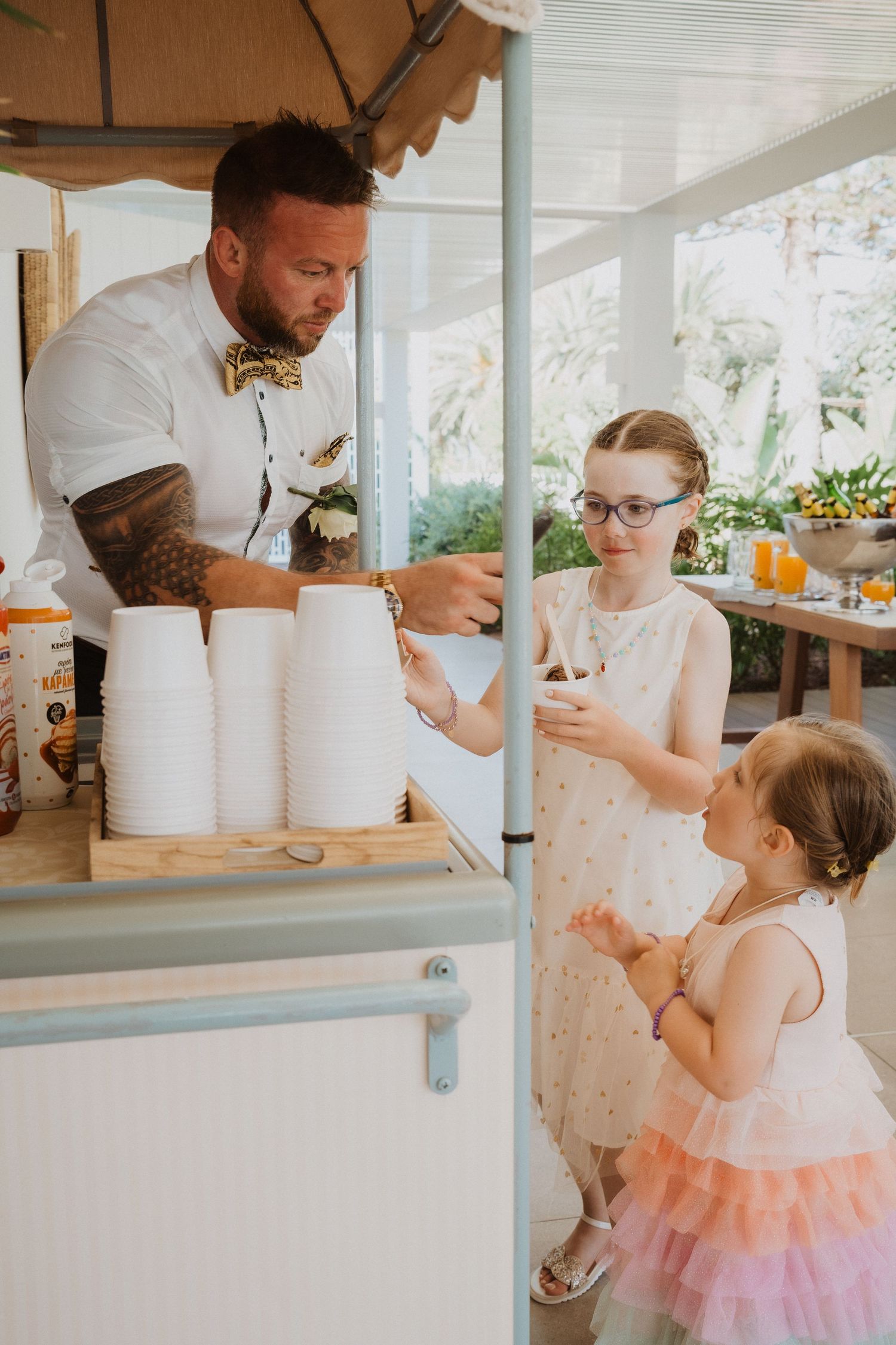Wedding vendor serves refreshments to young guests at outdoor reception.