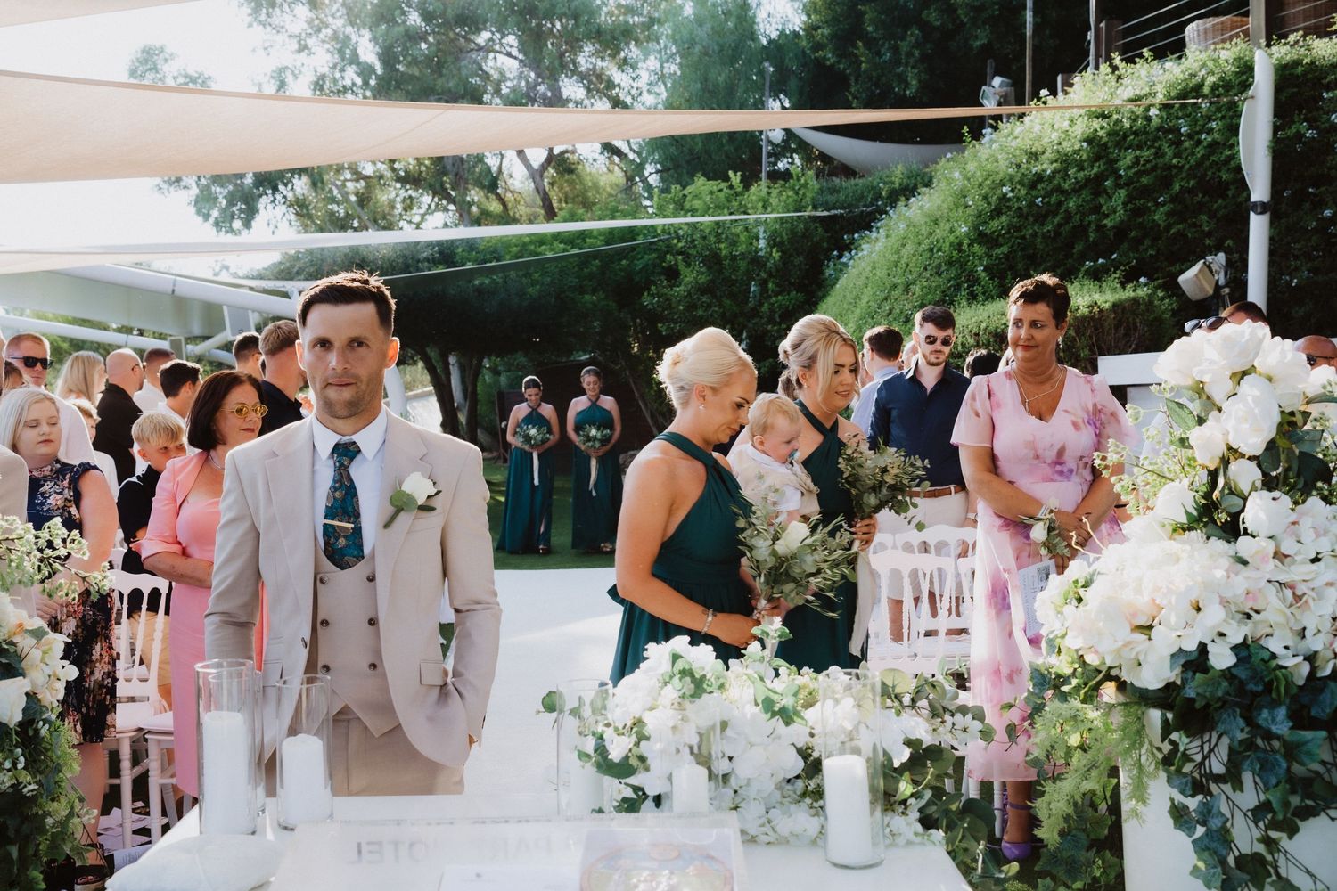 An outdoor wedding ceremony setup with white floral decorations and a covered canopy area.