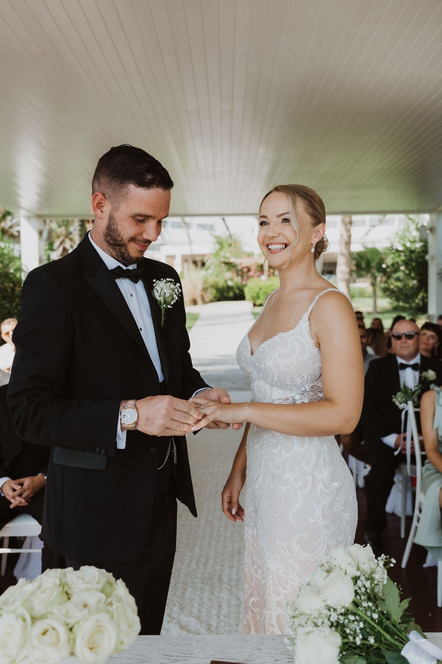Wedding ceremony moments showing couple exchanging rings under covered outdoor venue.