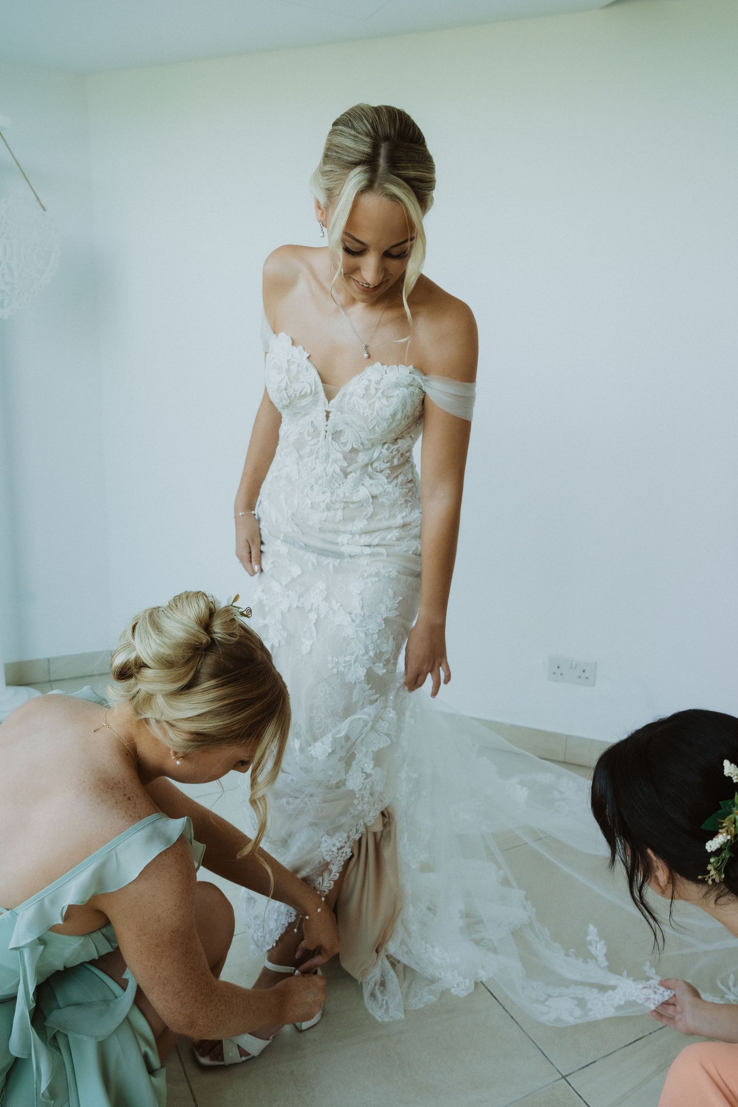 Bride in a lace wedding gown adjusting her dress while getting ready.