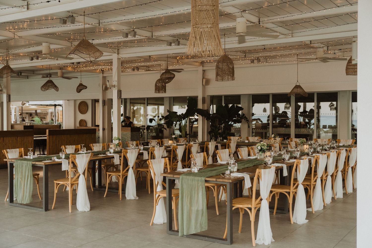 Large wedding reception space with rustic decor and natural lighting streaming through windows.