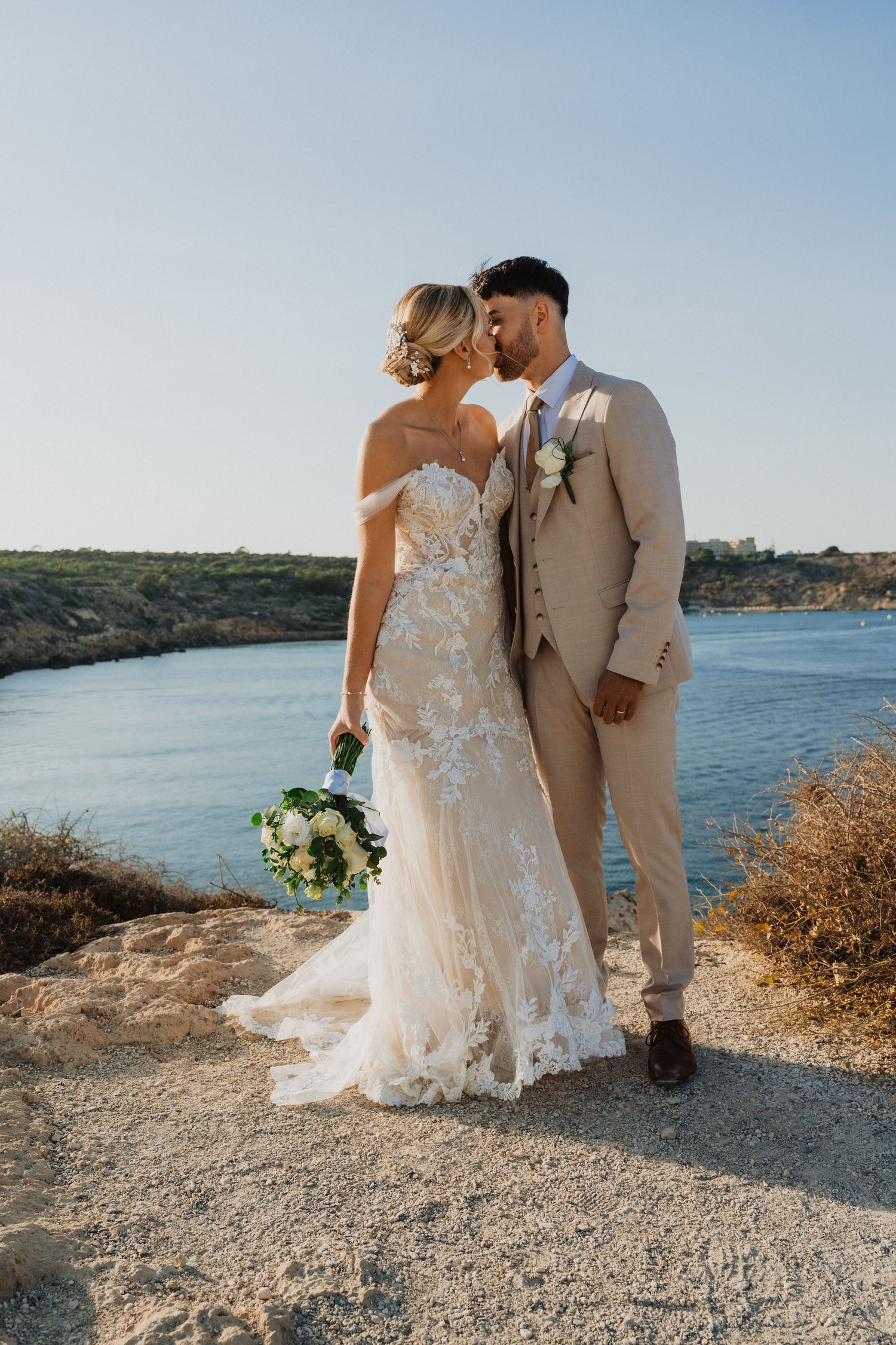 Wedding couple walks along a rocky coastal trail with beautiful ocean views on their special day.