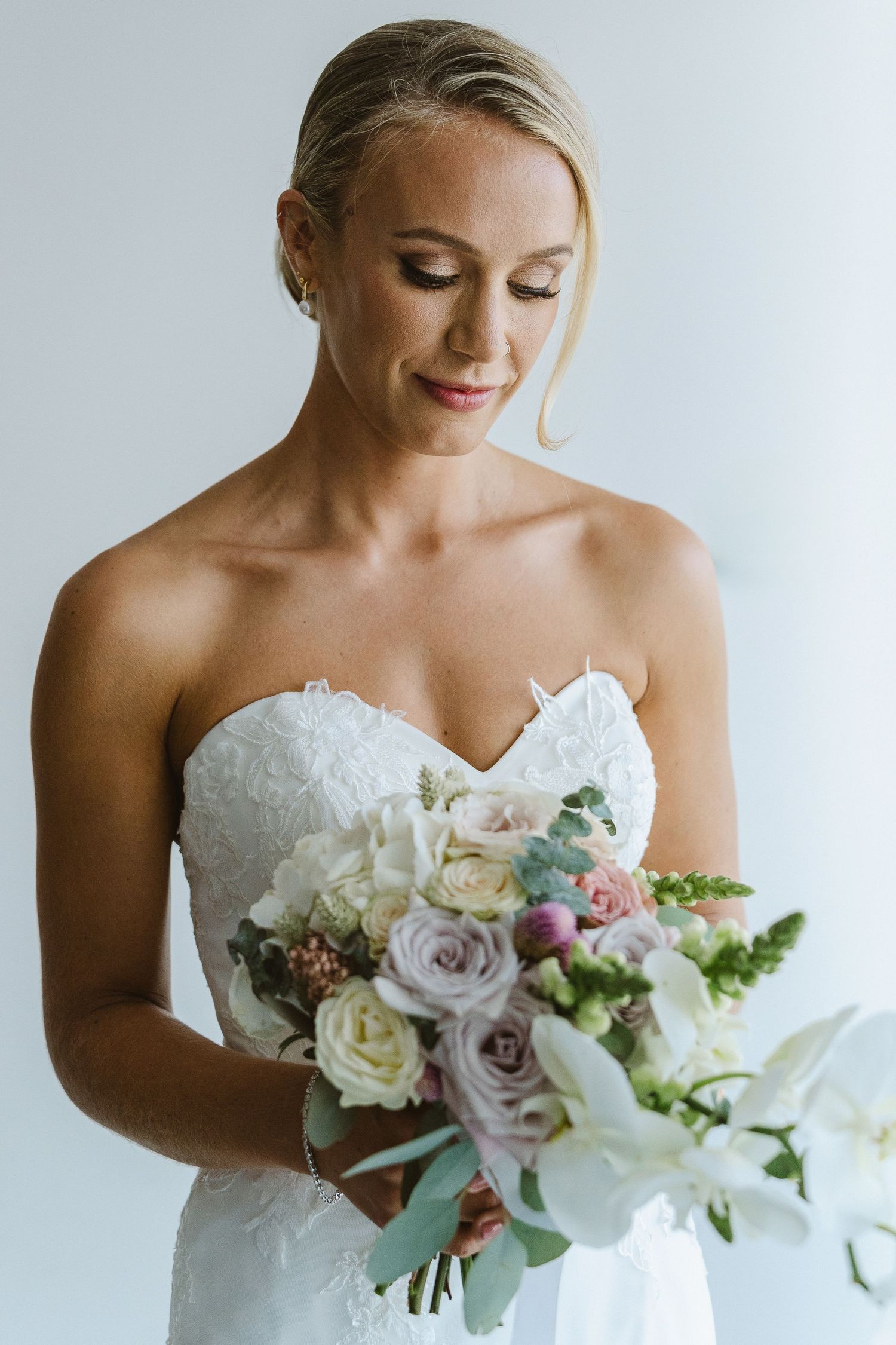 Close-up portrait of bride holding soft pink and white floral bouquet.