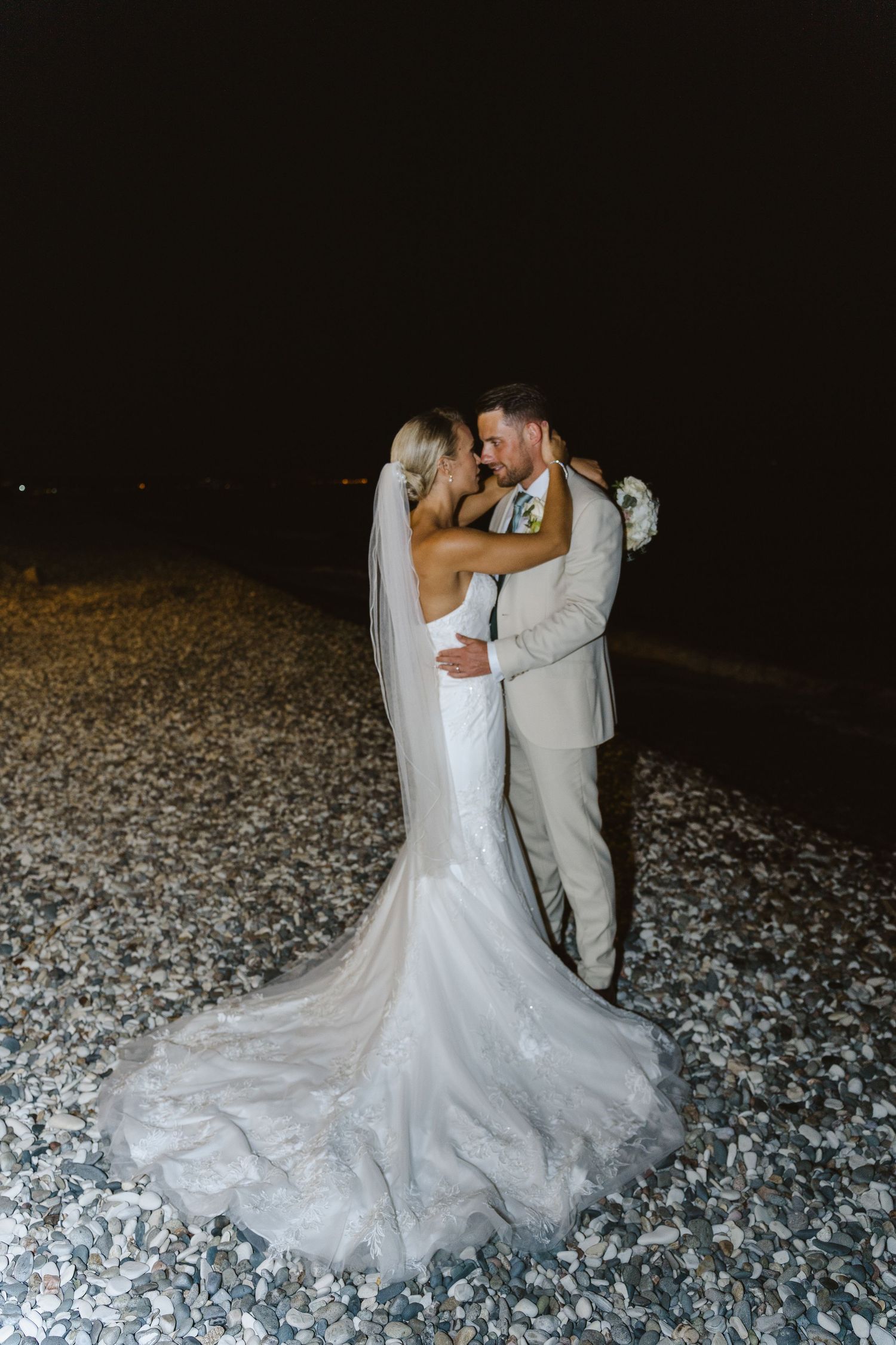 Romantic nighttime beach wedding portrait showcasing a beautiful lace train.