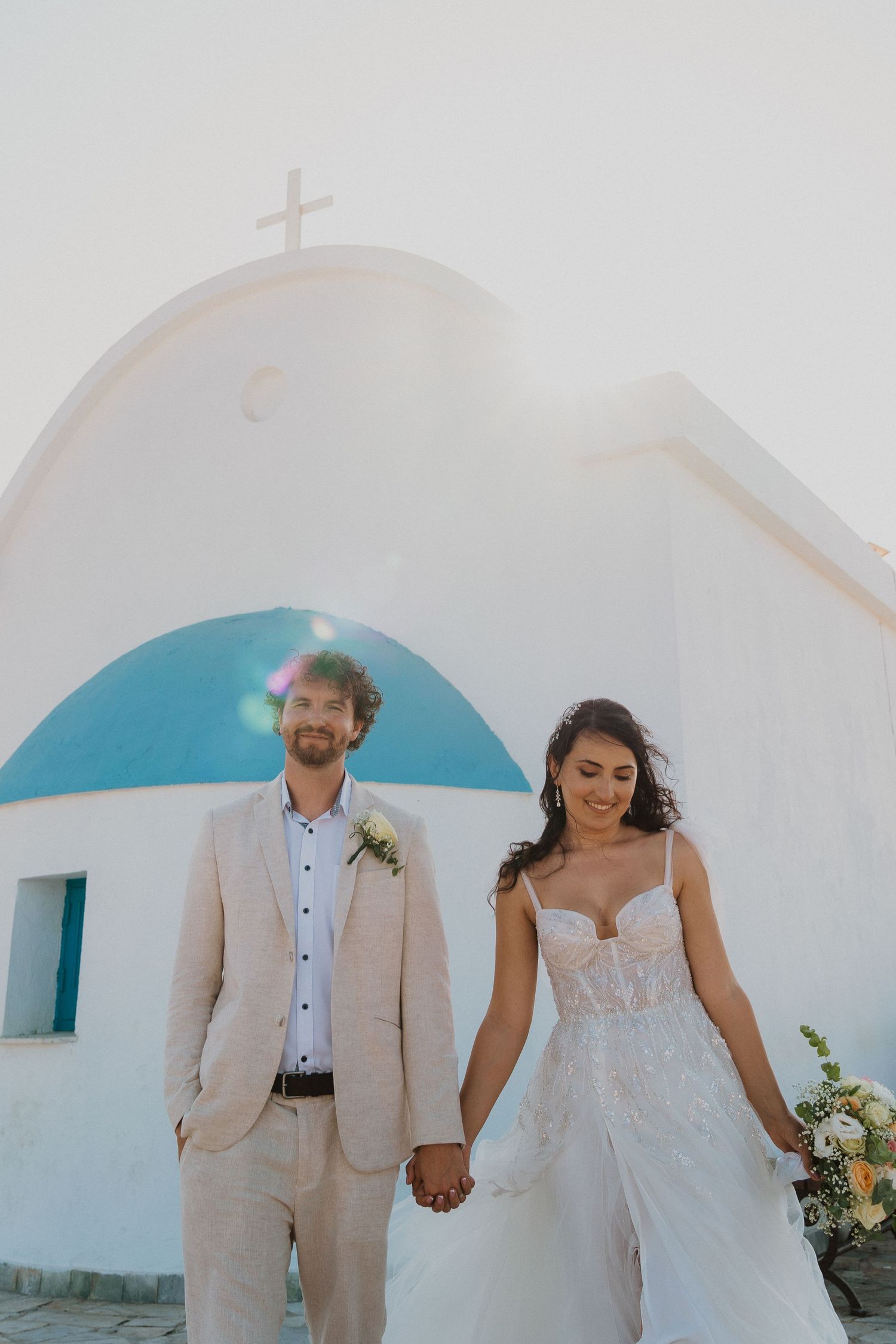 Elegant destination wedding portrait in front of classic Cycladic church architecture.