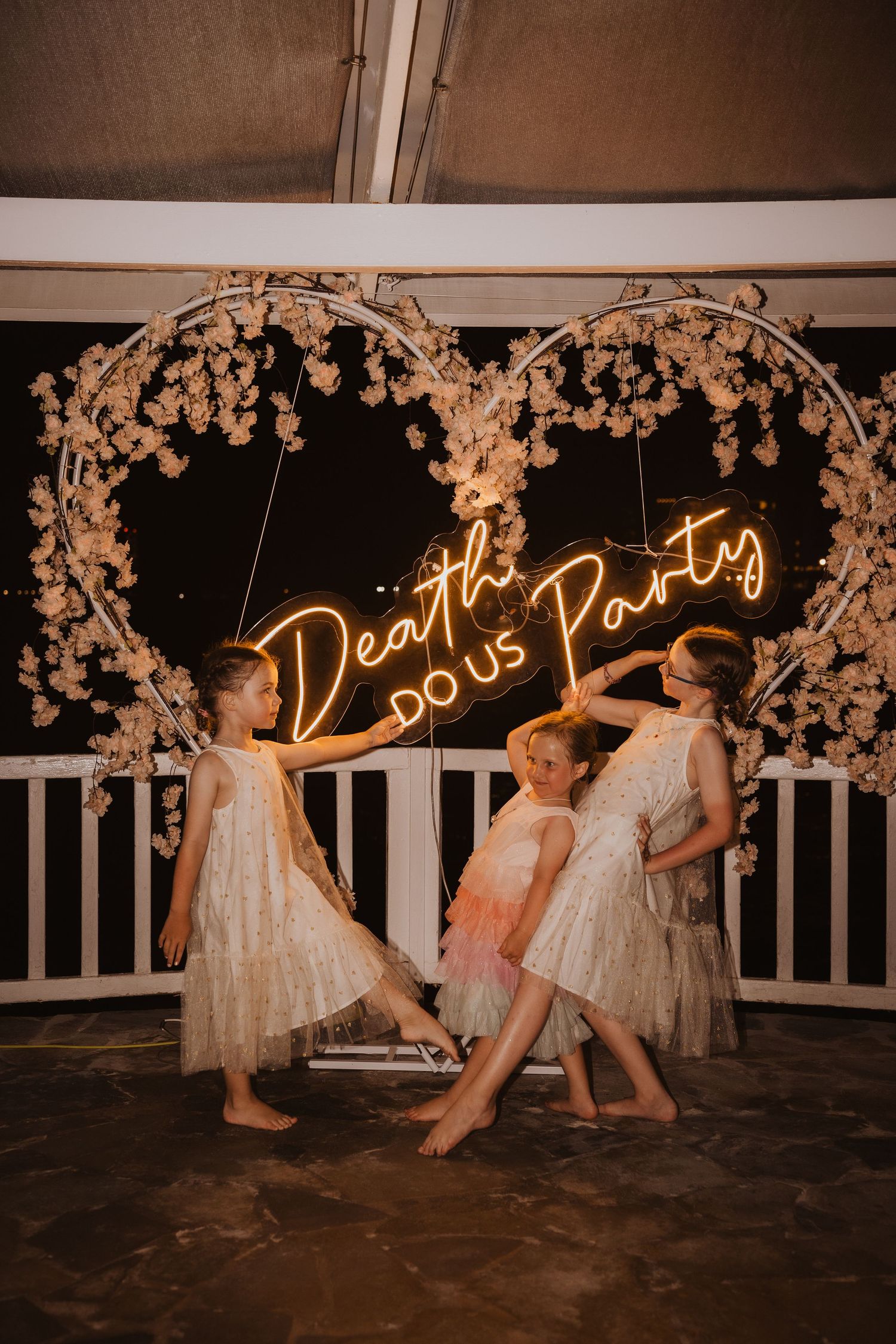 Illuminated 'Dance Party' neon sign framed by decorative floral arch at night.