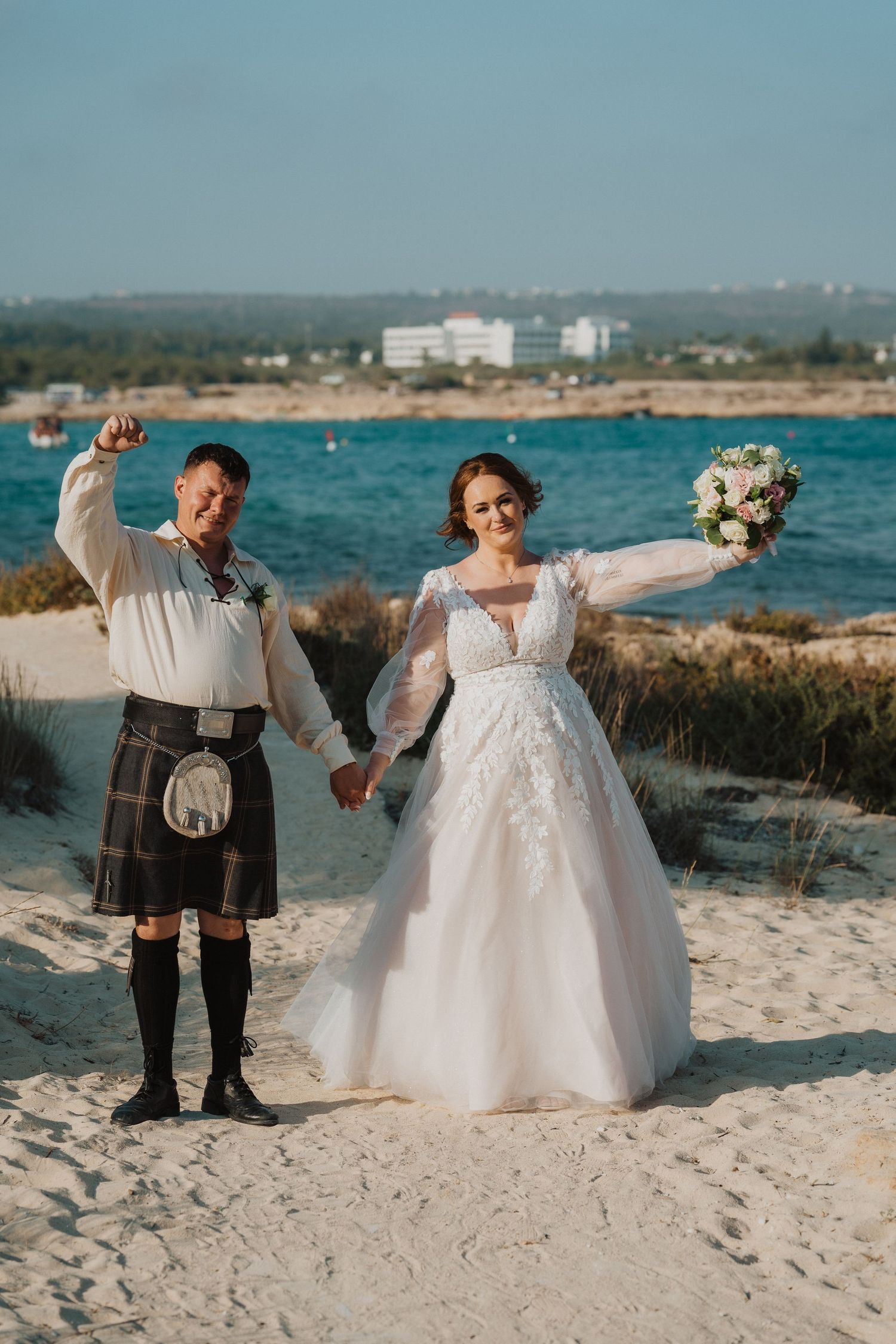 A celebratory beach wedding moment with blue ocean waters and coastal scenery.