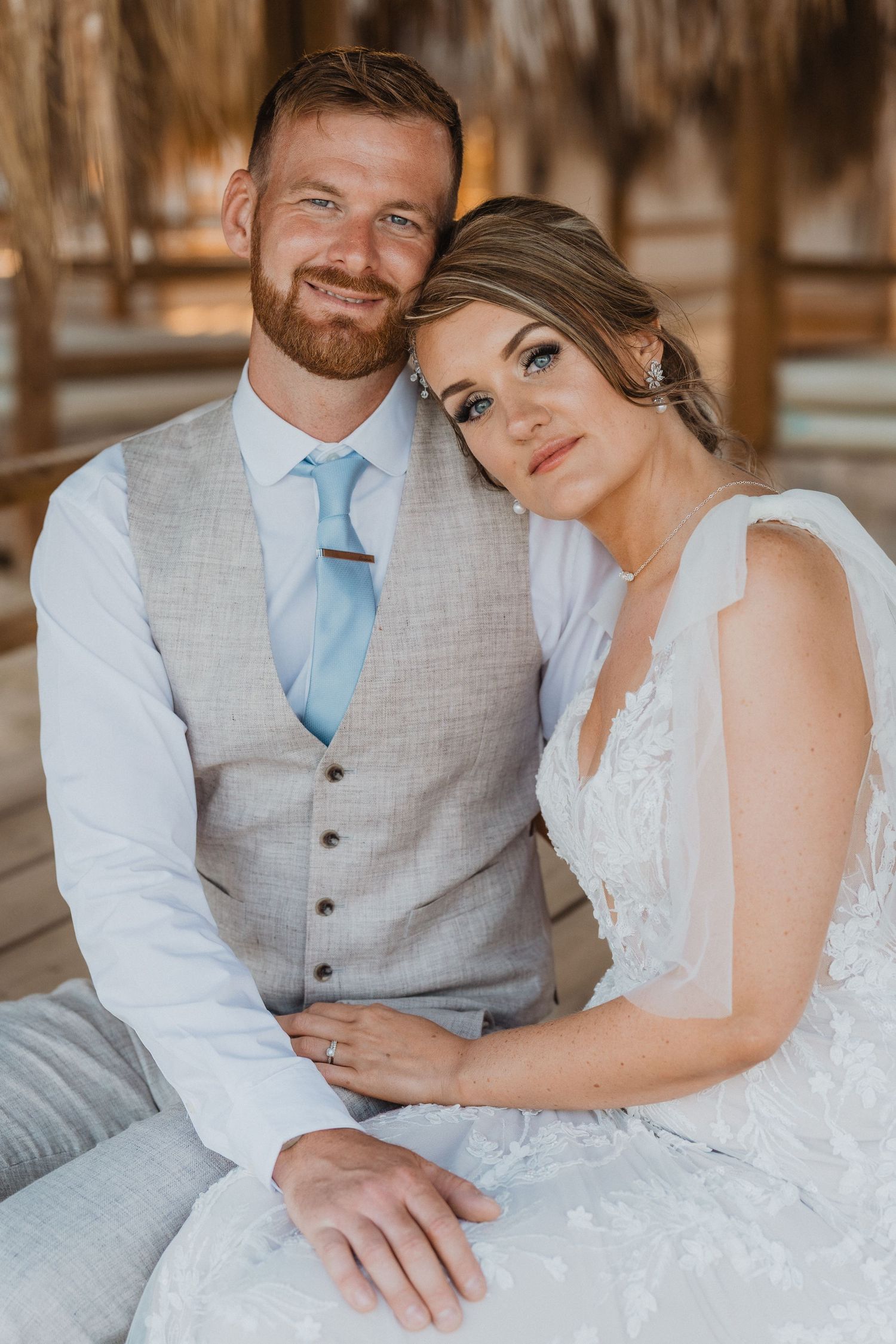 Romantic beach wedding portraits showing tender moments between couple on wooden deck.