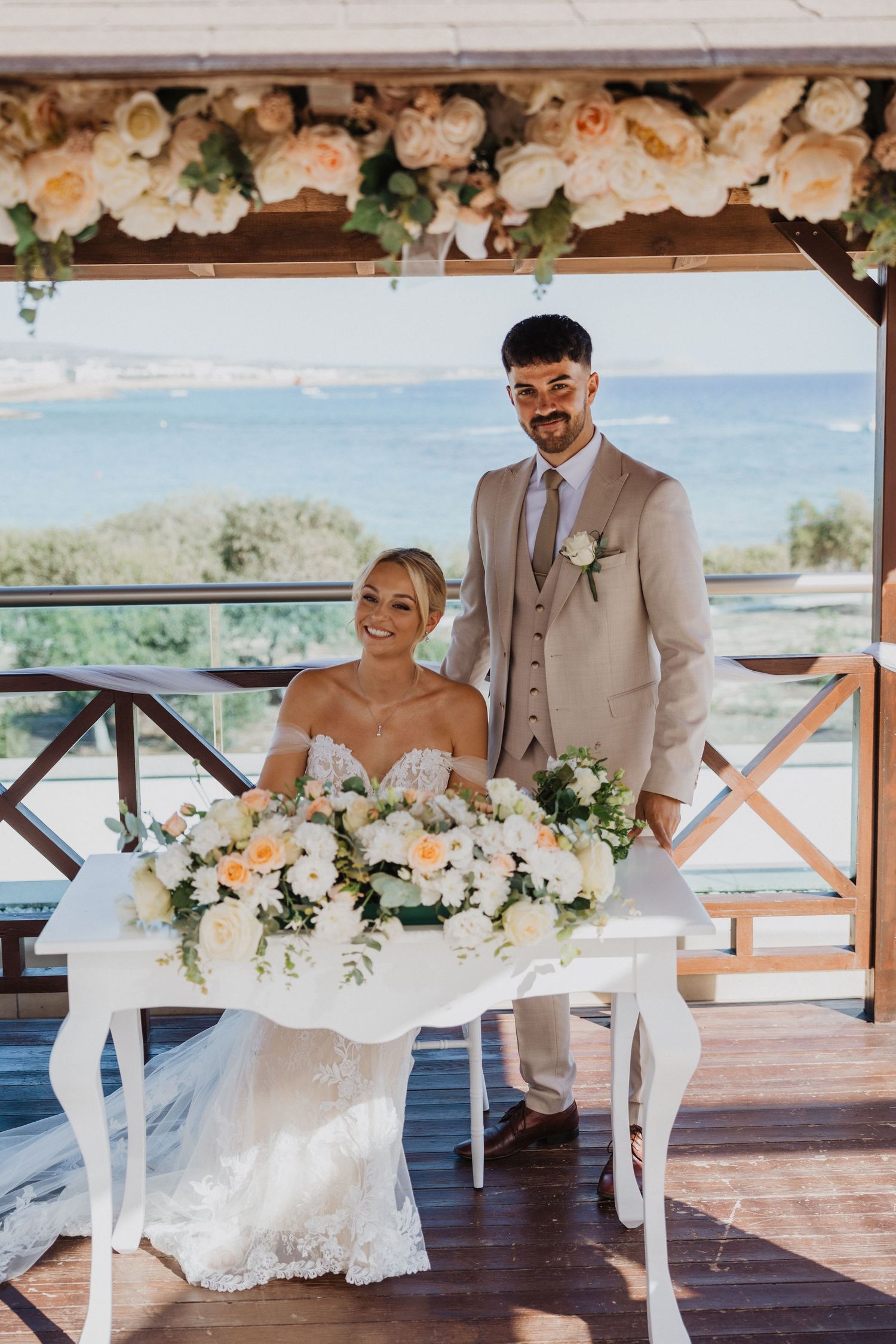 Beachfront wedding ceremony setup with white floral arrangements and ocean views.