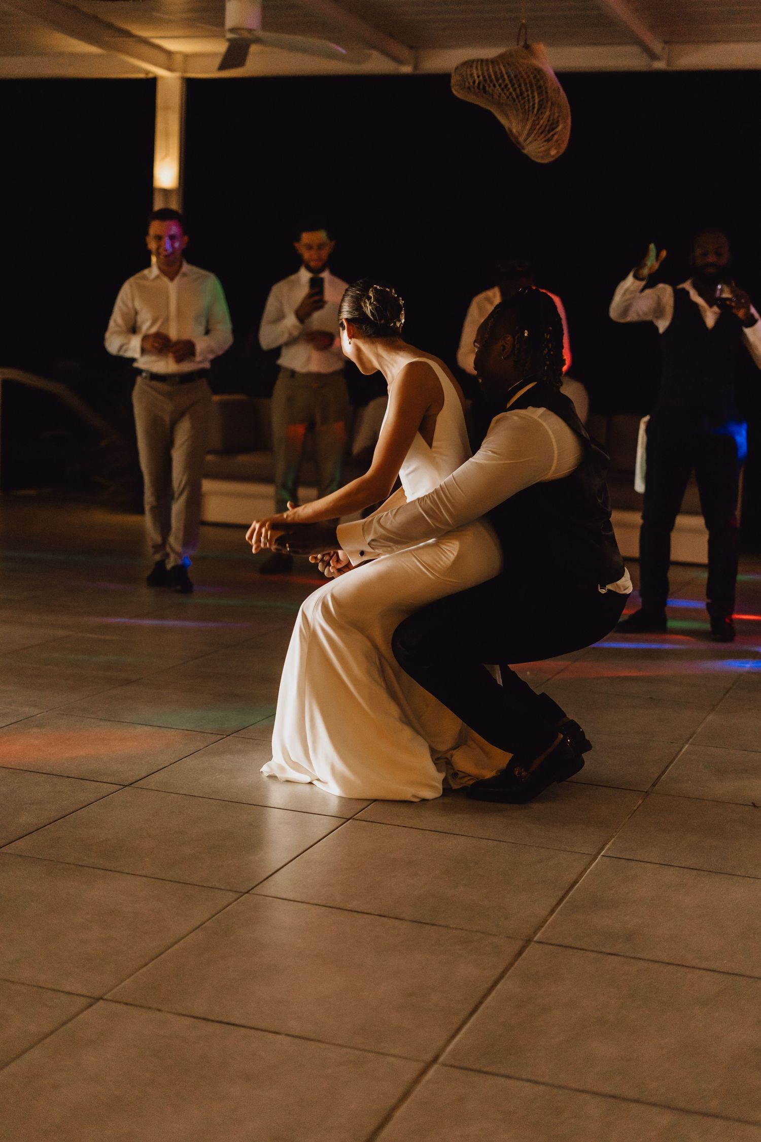 A dramatic dance dip performed during a wedding reception with spectators in the background.