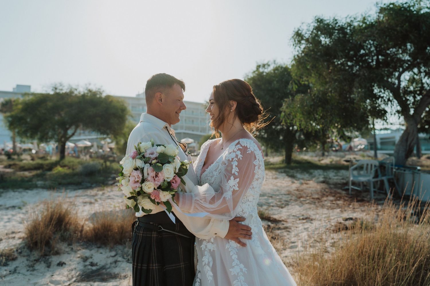 A tender moment between newlyweds against a coastal backdrop during golden hour.