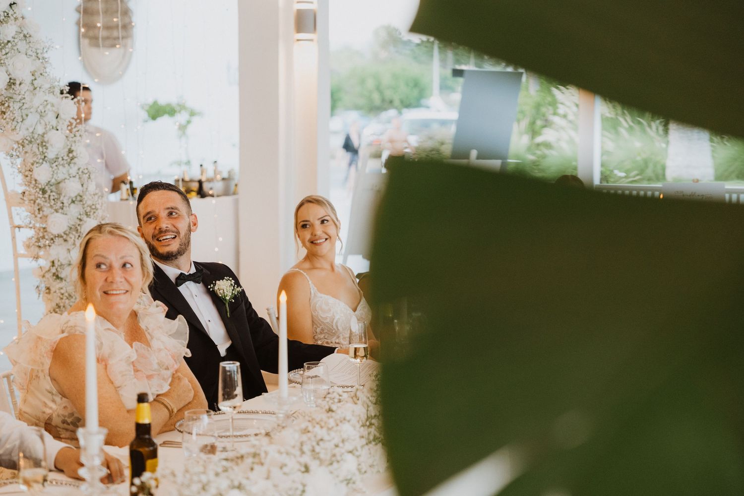 Wedding reception celebration with crystal chandeliers and elegant decor in a bright venue.