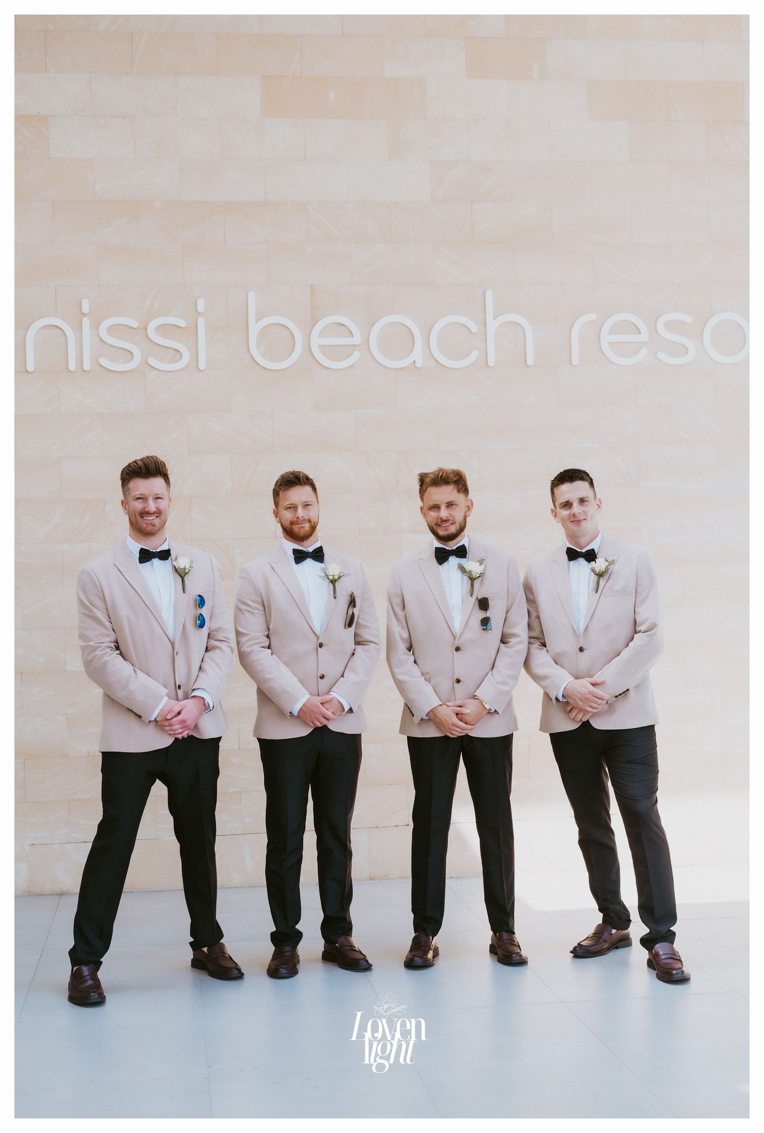 Groomsmen in matching beige jackets and black pants posing at Nissi Beach Resort.