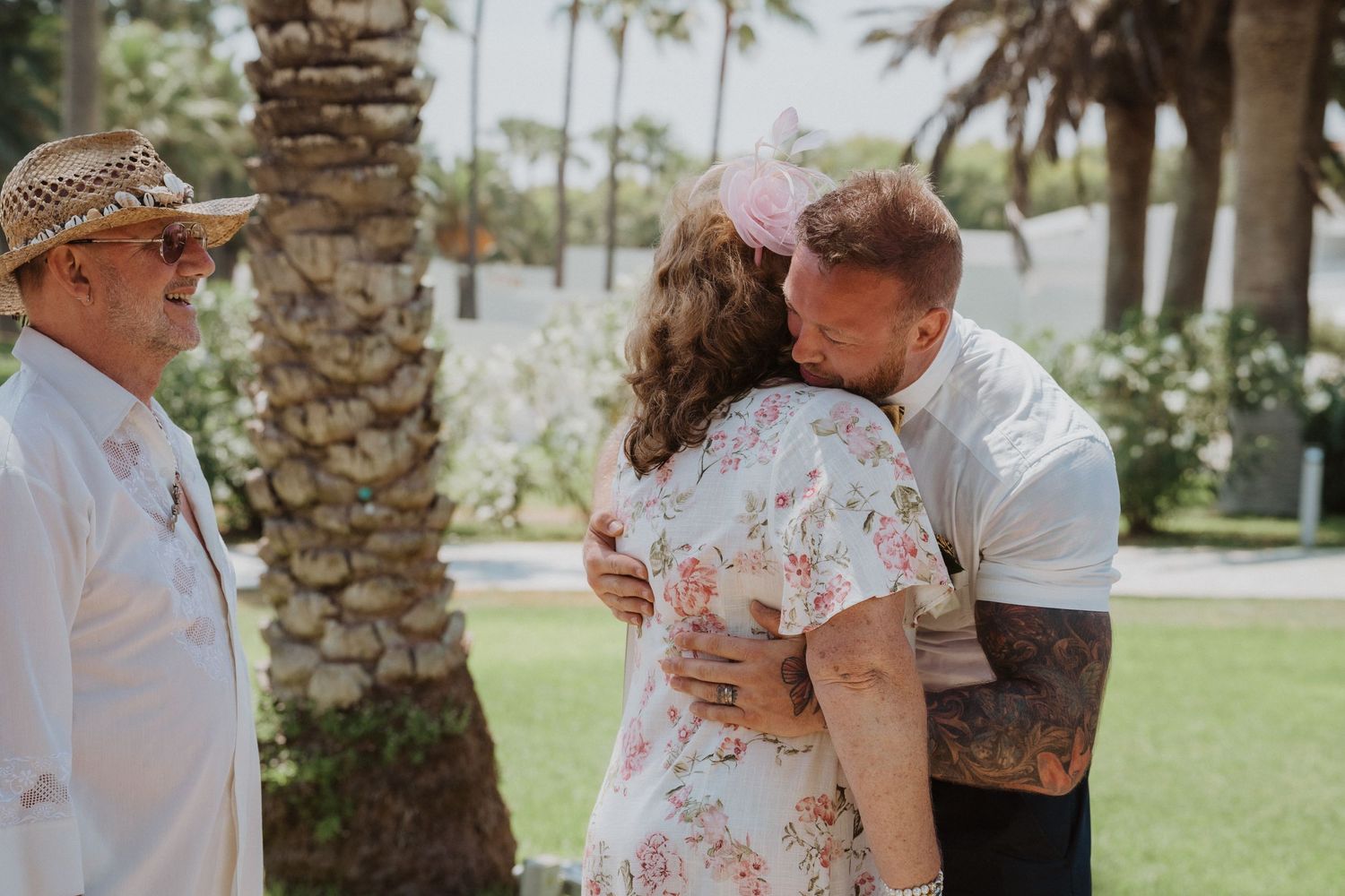 Intimate moment shared during outdoor wedding celebration near tropical palm trees.