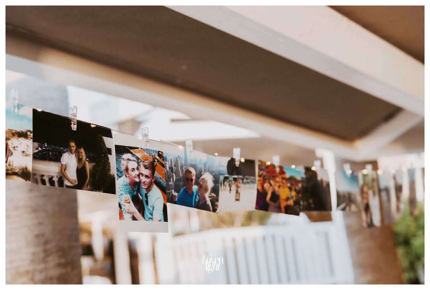 Collection of photos displayed on string at wedding reception venue.