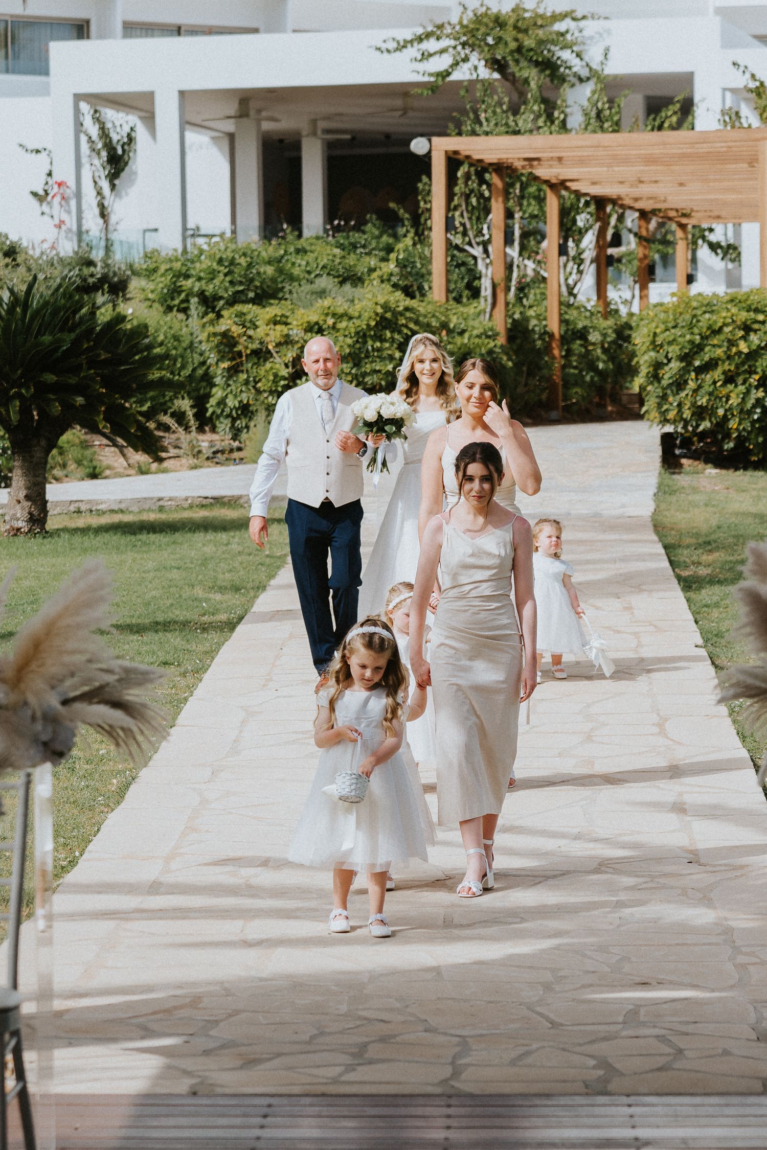 Wedding party walking down a stone pathway with tropical garden landscaping.