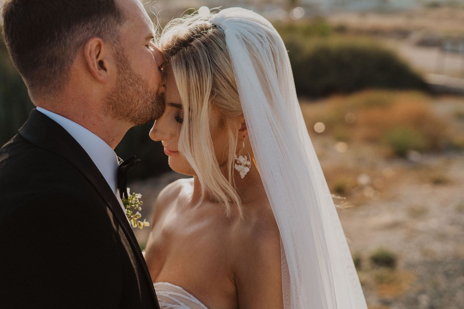 Intimate close-up wedding portrait against Mediterranean coastal backdrop.