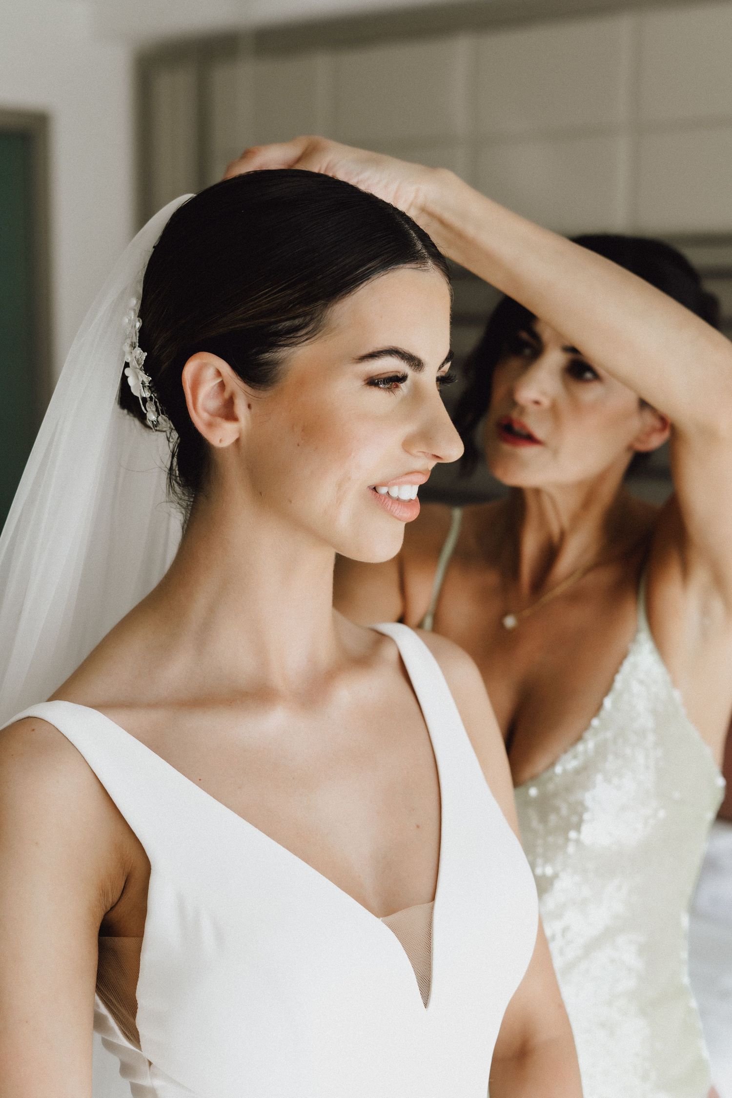 Two women sharing an intimate moment while preparing for a wedding with one wearing a veil.