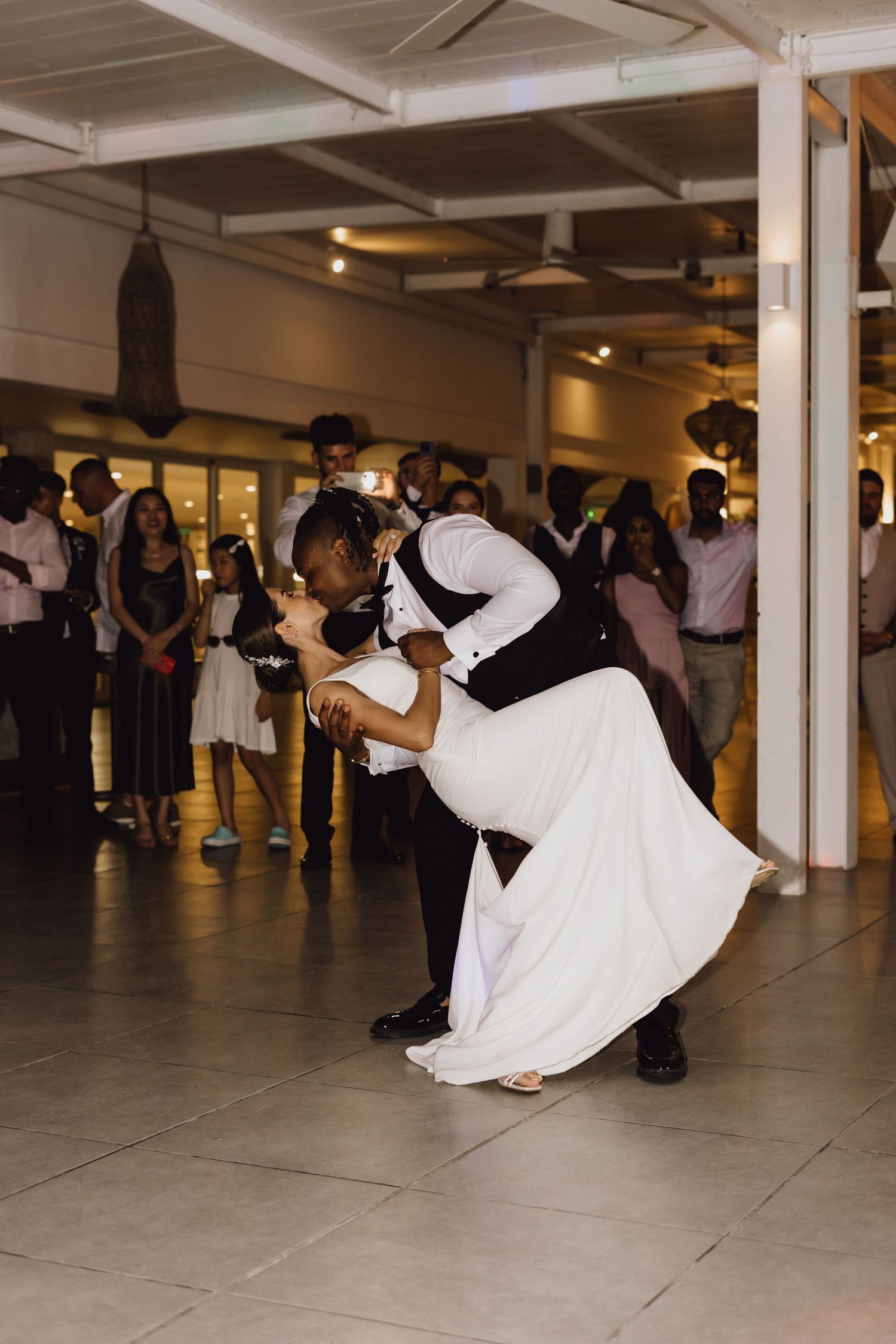 Couple performing an intimate dip during their wedding dance under industrial ceiling lights.