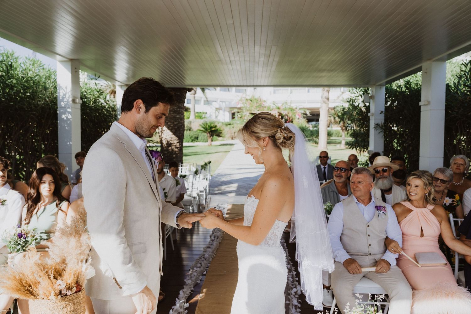 Wedding party and guests celebrate under a covered outdoor venue with natural lighting.