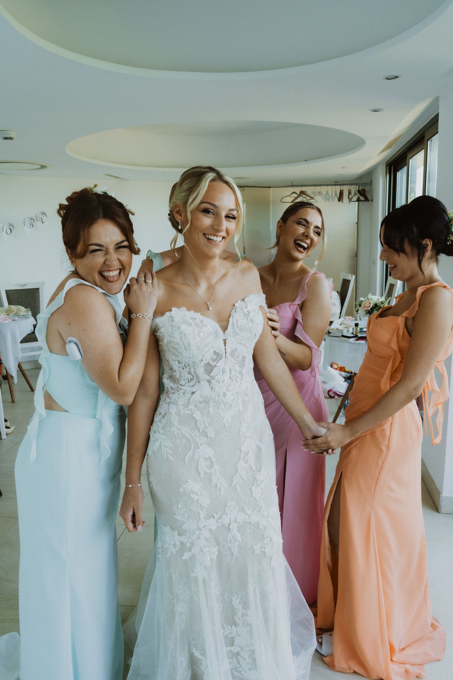Wedding preparation scene with pastel colored dresses in a bright modern room.