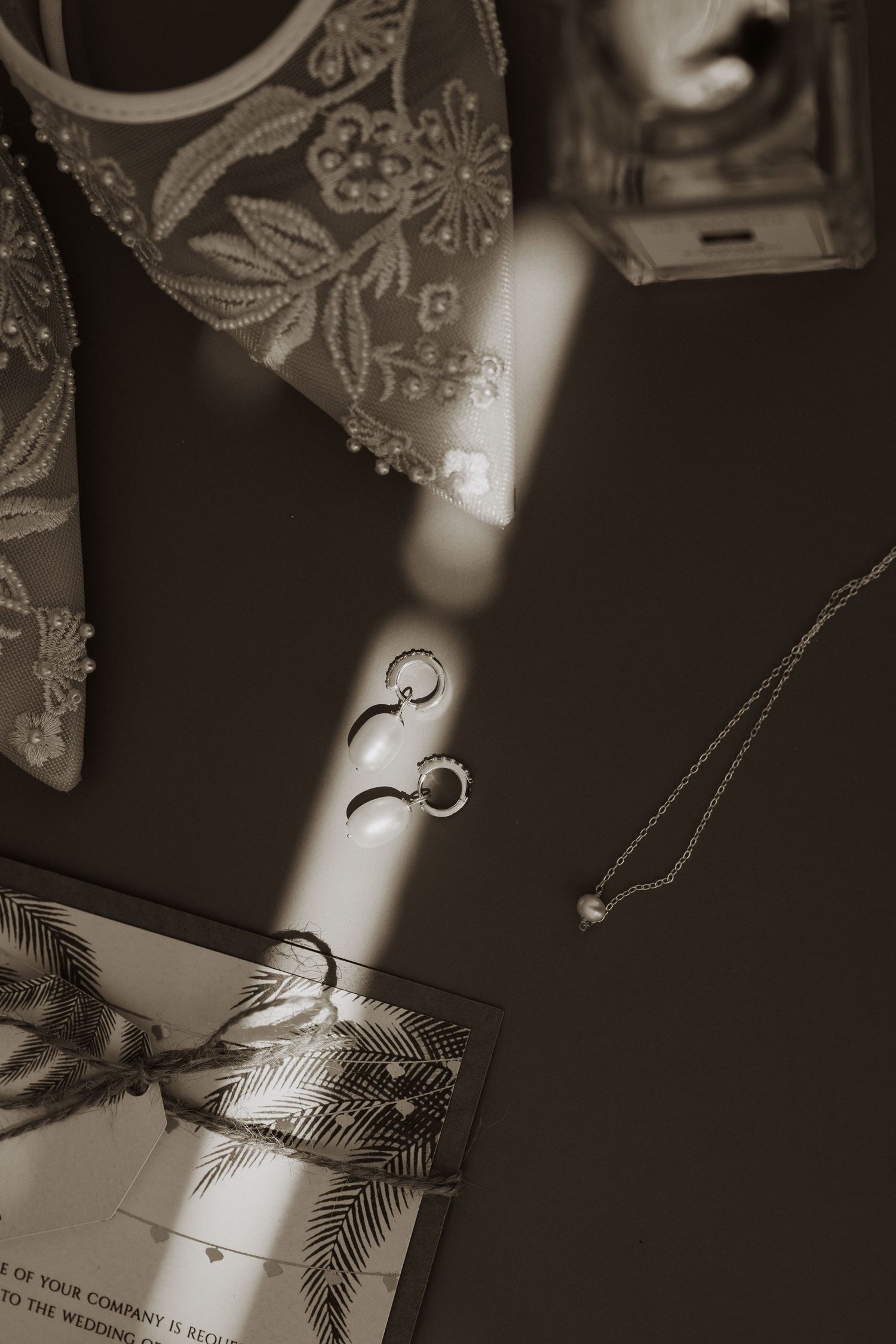 Black and white photo of an engagement ring casting dramatic shadows on a book page with earrings. Lovenlight photography
