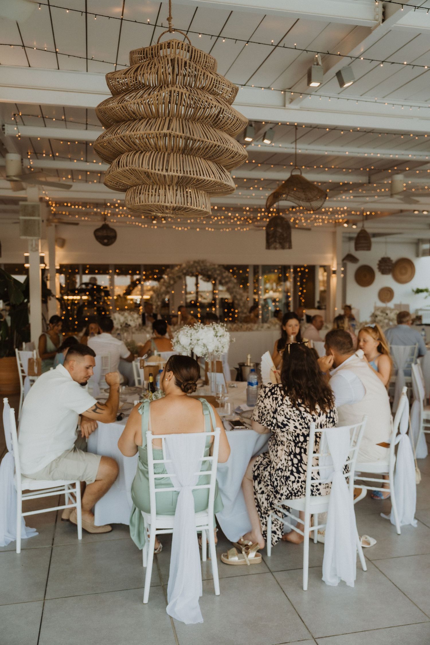 Reception venue decorated with rattan pendant lights and string lights creating a warm atmosphere.
