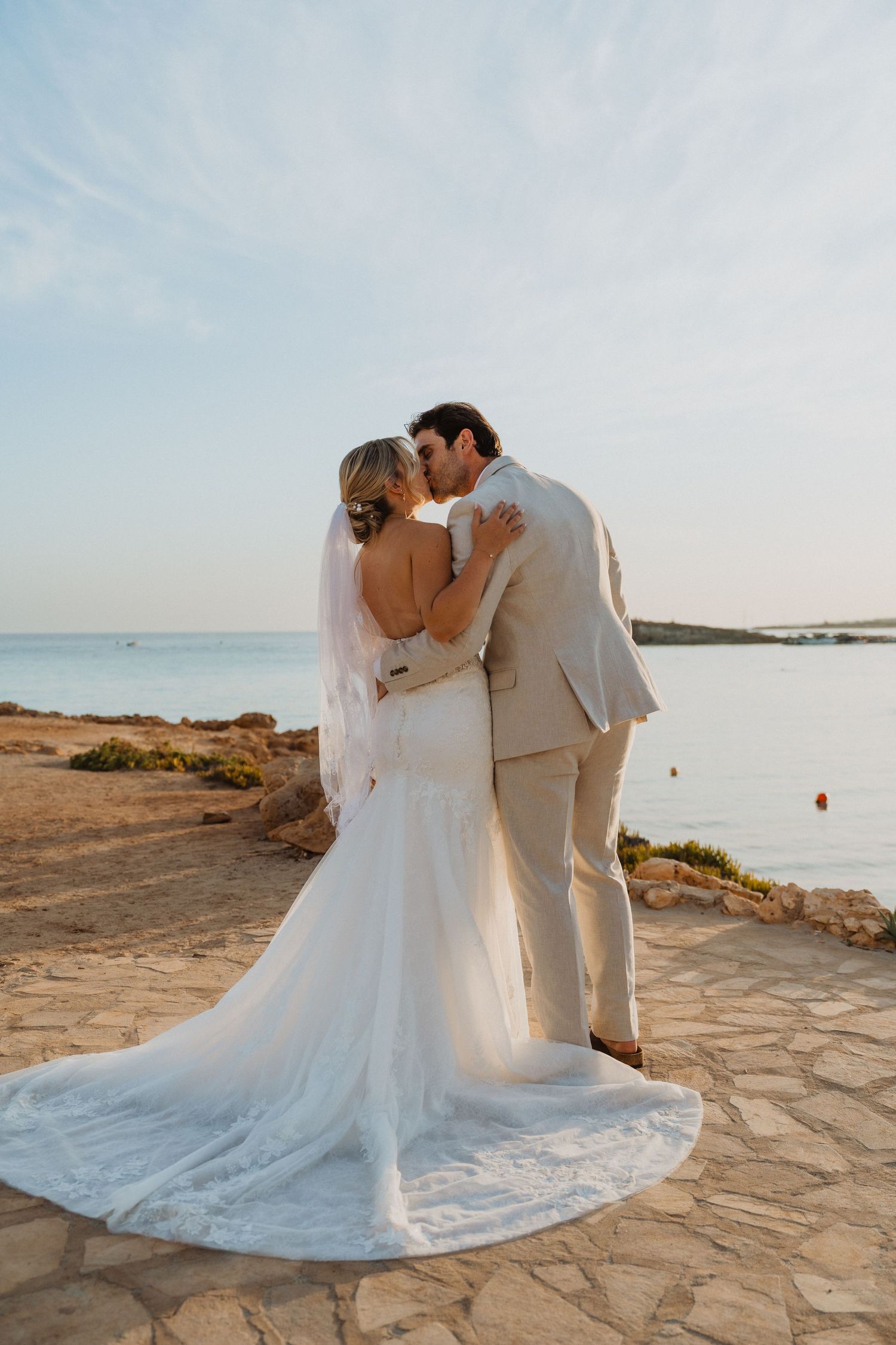 Elegant wedding couple poses on stone pathway with sweeping ocean views.
