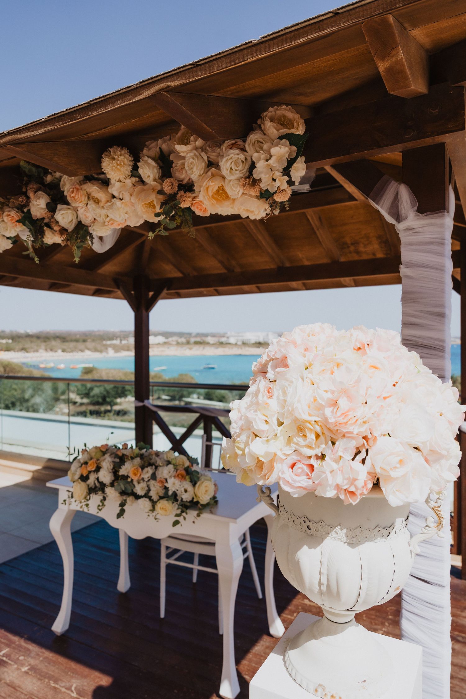 Wedding venue gazebo decorated with white and peach floral arrangements overlooking the sea.
