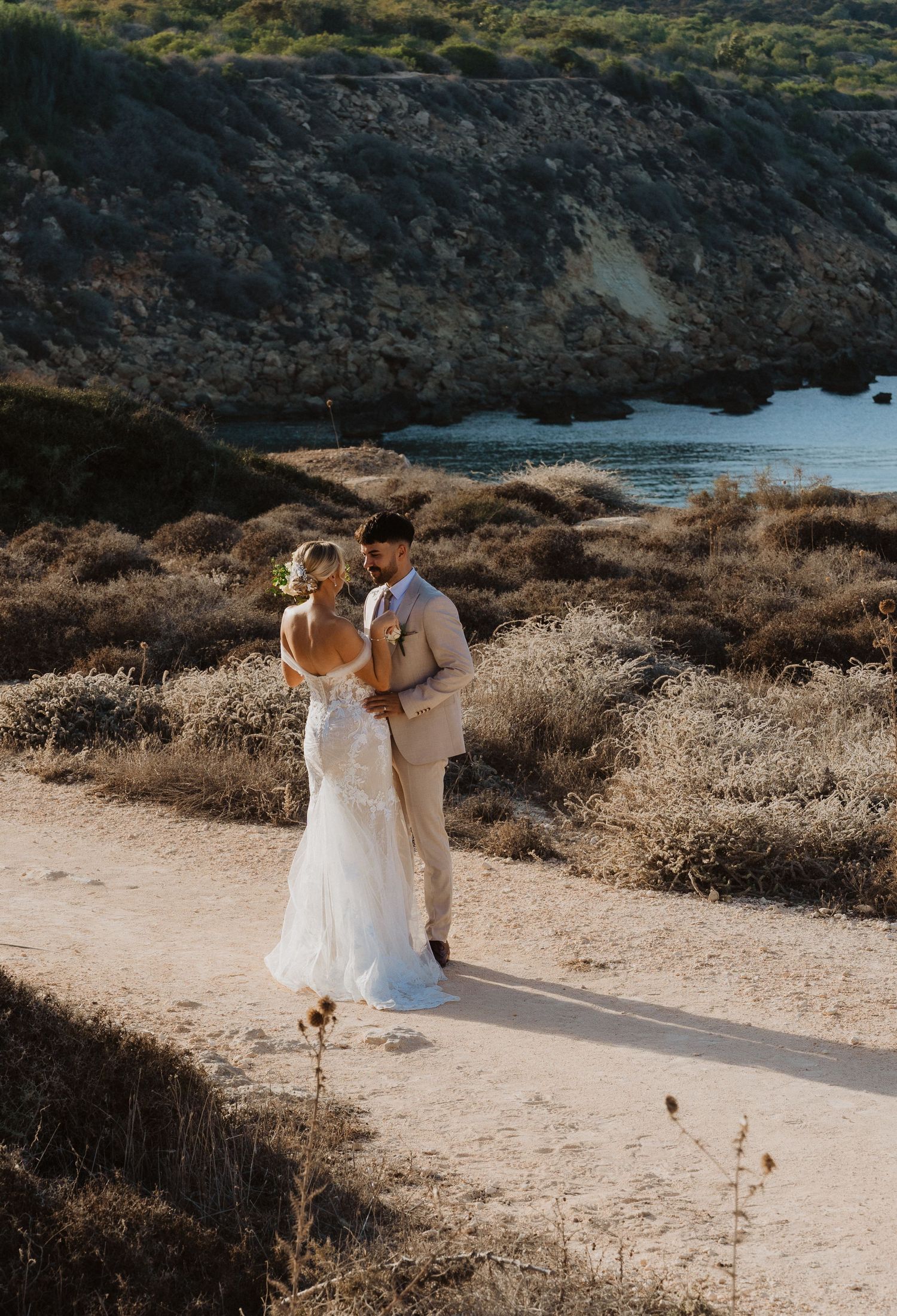 Couple sharing a romantic moment on a scenic coastal path overlooking the Mediterranean.