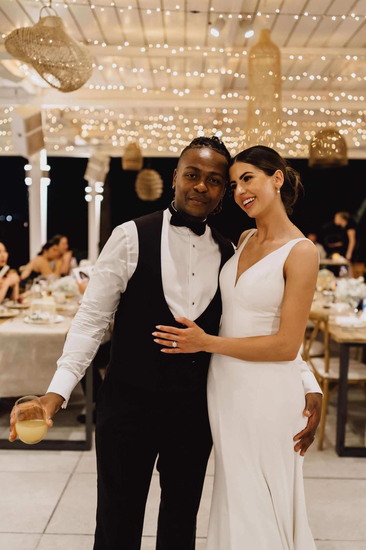 Elegant wedding couple shares a special moment during their reception under string lights.