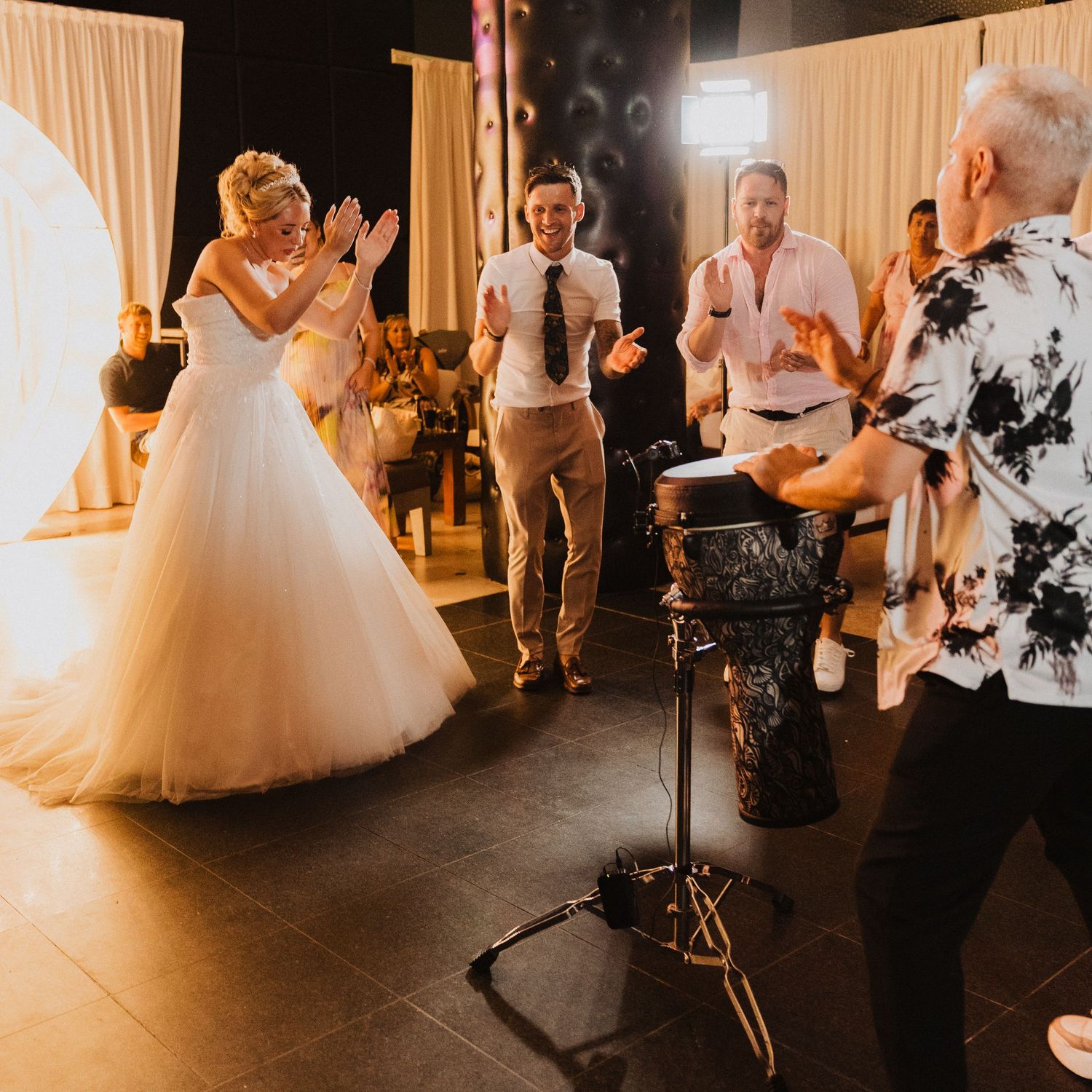 Wedding celebration with dance party atmosphere as guests dance enthusiastically under warm lighting at an indoor reception.