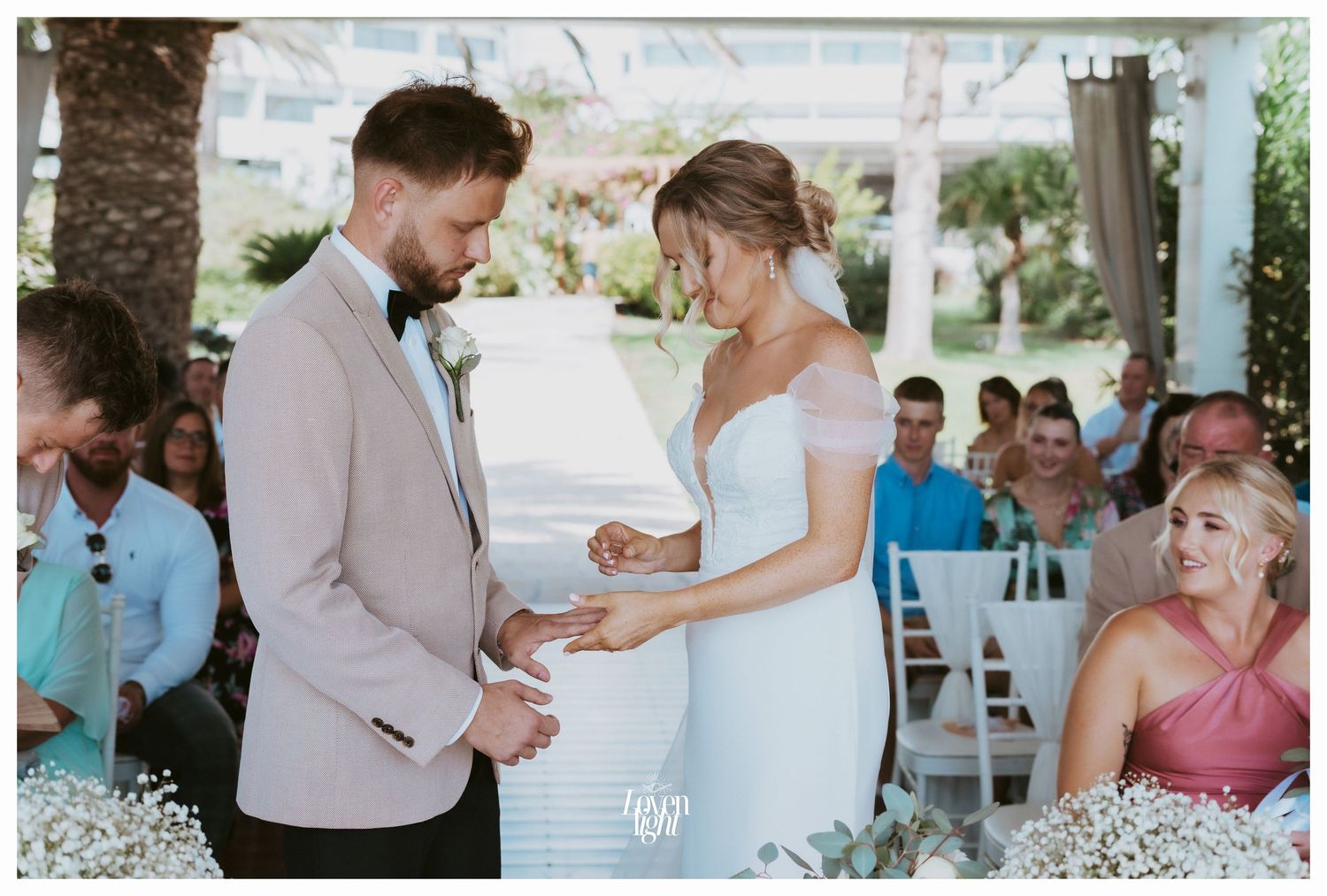 Beautiful outdoor wedding ceremony with guests seated on white chairs and blue accents.