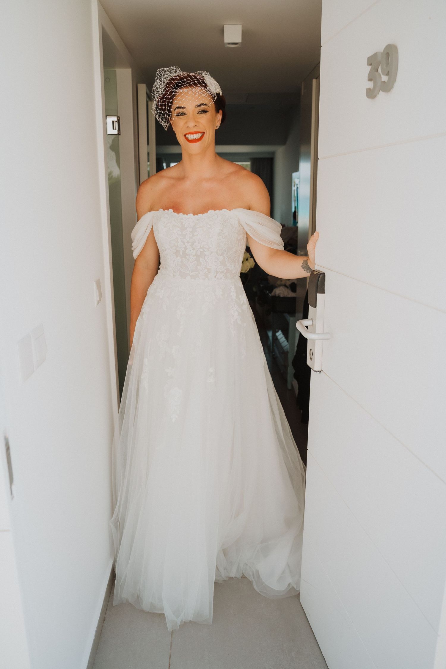 Wedding dress with off-shoulder design and tulle skirt illuminated in hallway.