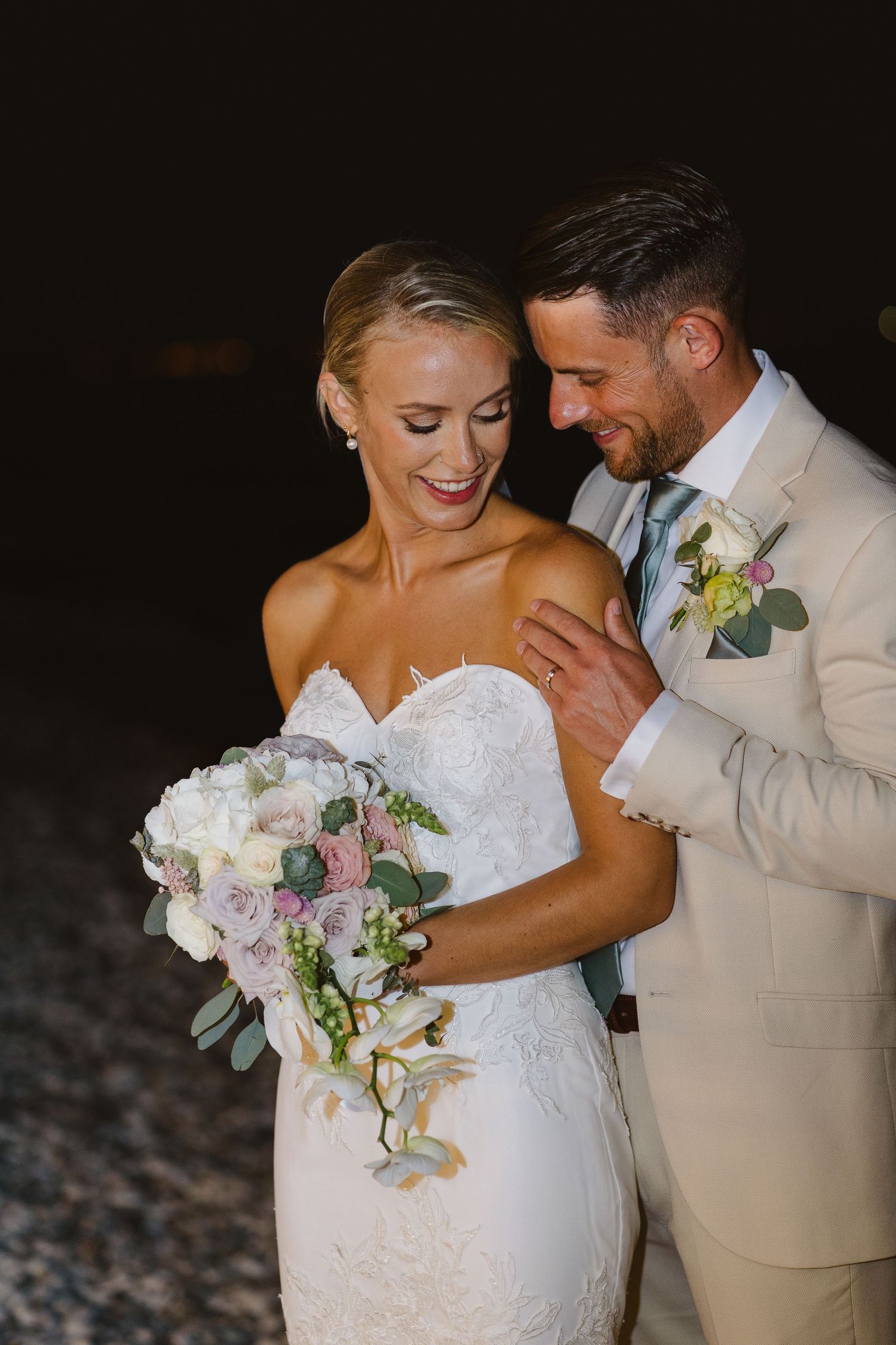 Intimate wedding moment captured on beach with couple sharing joyful laughter.
