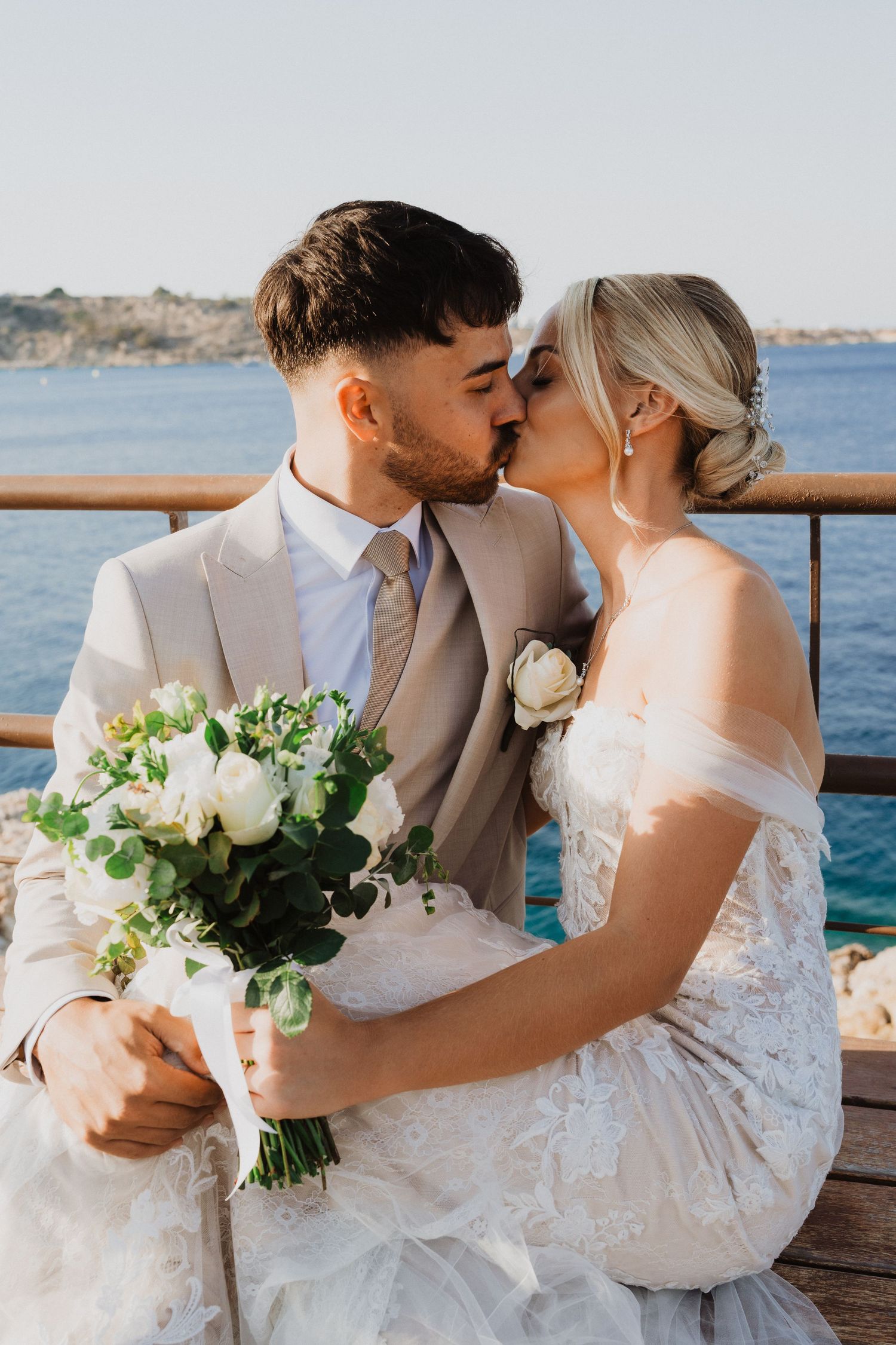 Romantic seaside wedding portraits captured on wooden pier with ocean backdrop.