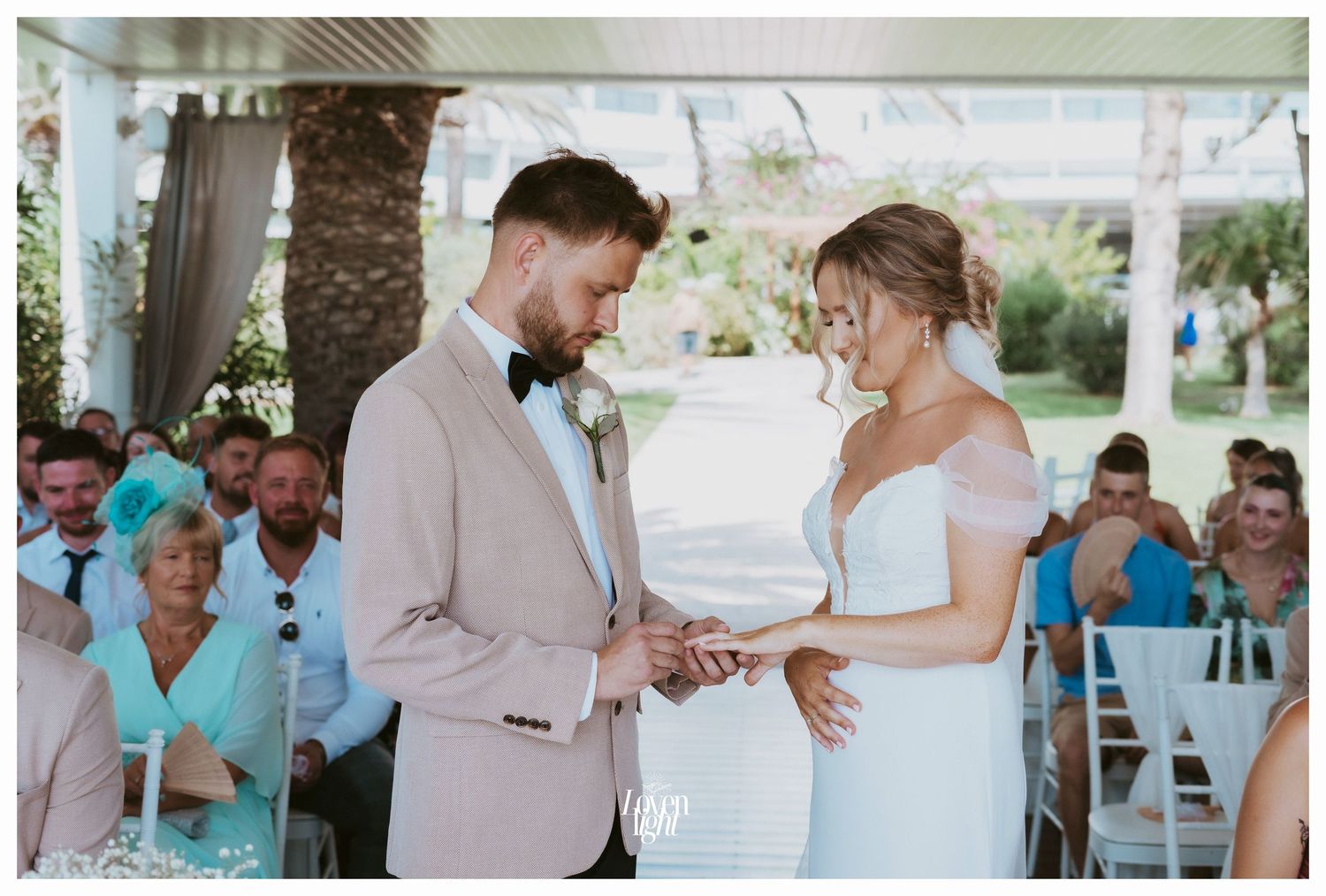 An intimate wedding ceremony moment under a covered patio with guests in turquoise attire.