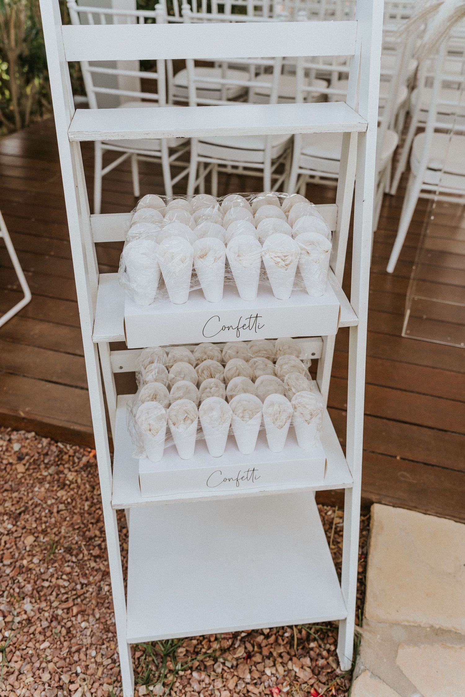 White wooden ladder shelf displaying rows of confetti cones for a wedding ceremony.