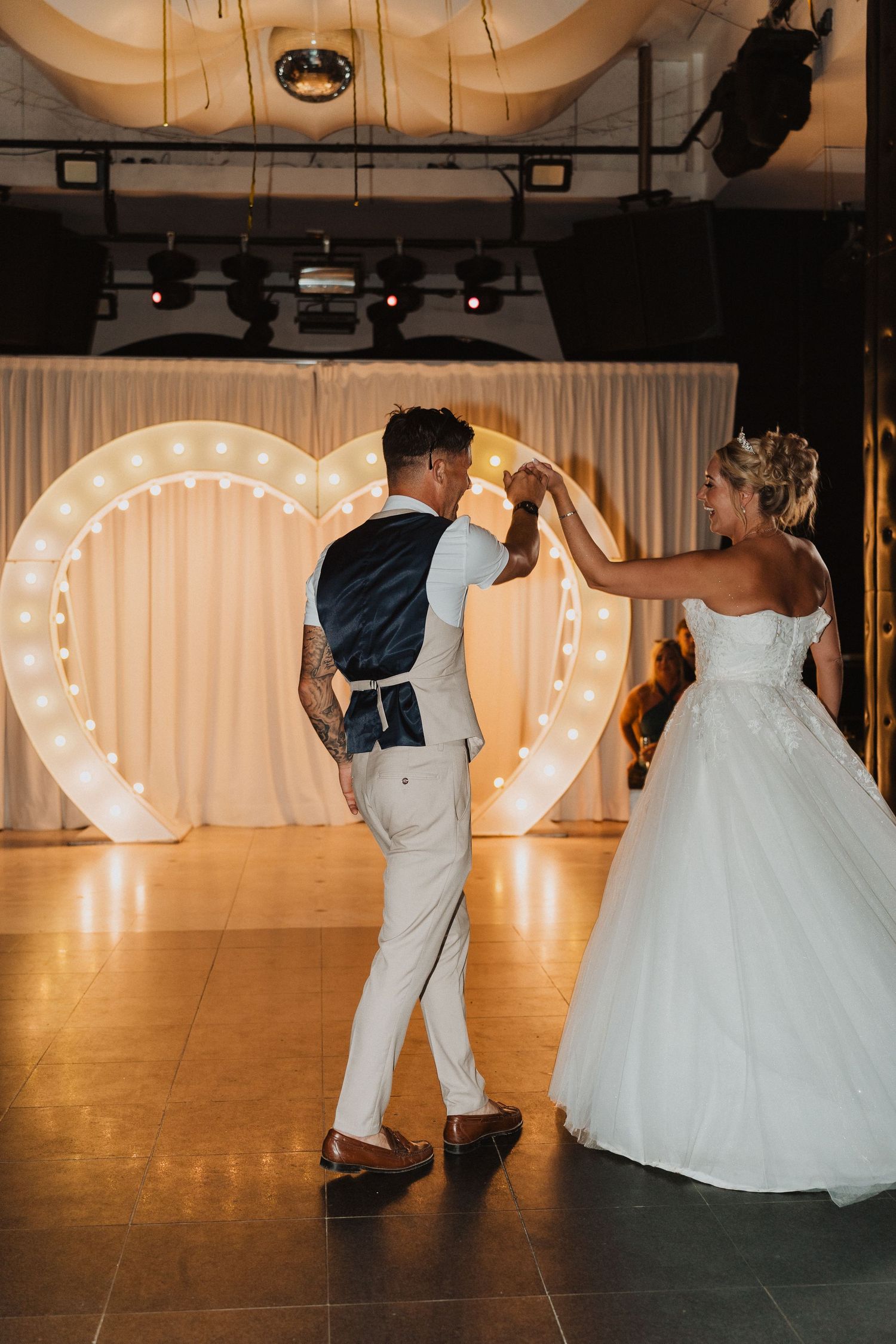 First dance in front of illuminated heart backdrop at wedding reception.