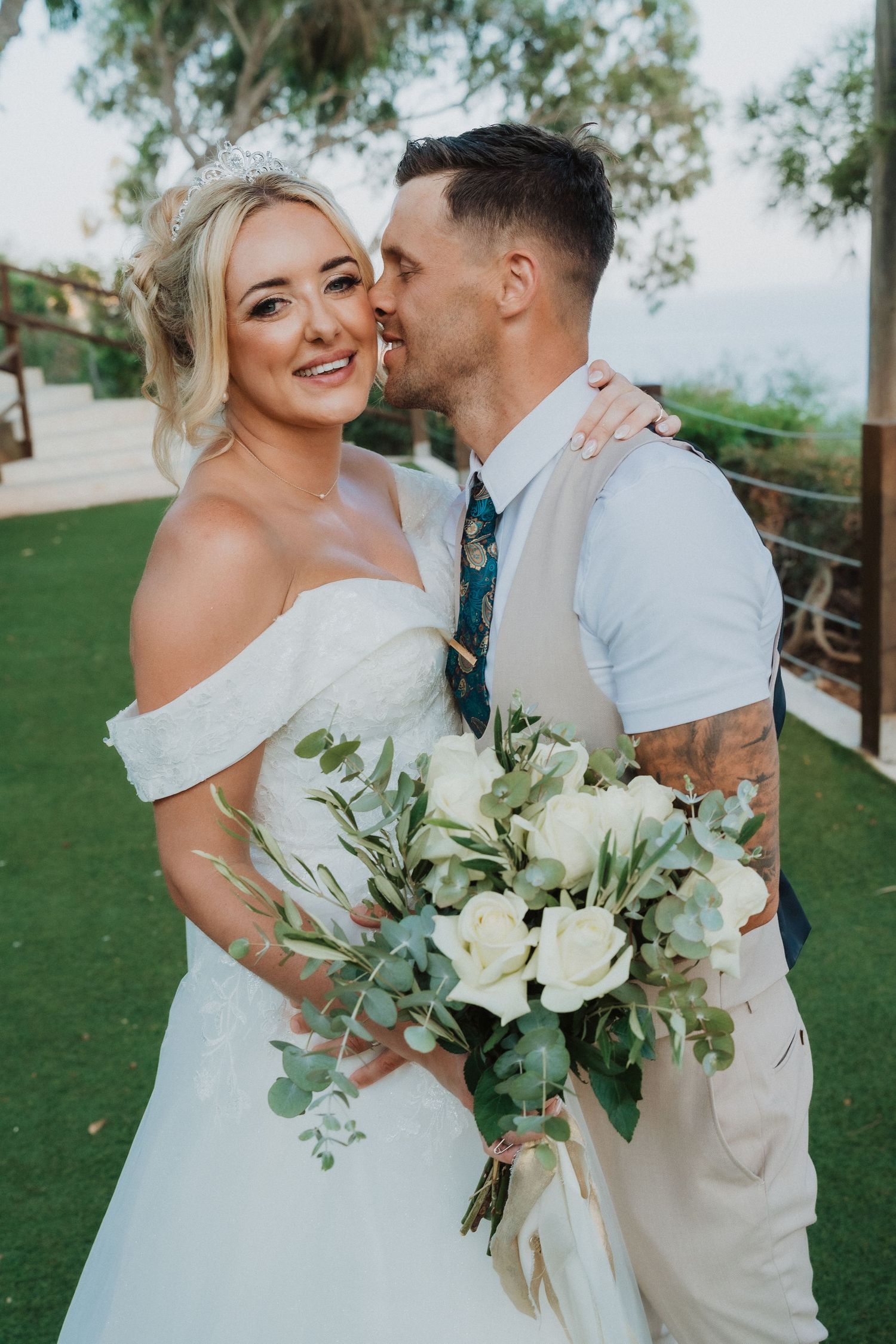 A tender wedding moment captured with a beautiful white bouquet featuring roses and eucalyptus greenery.