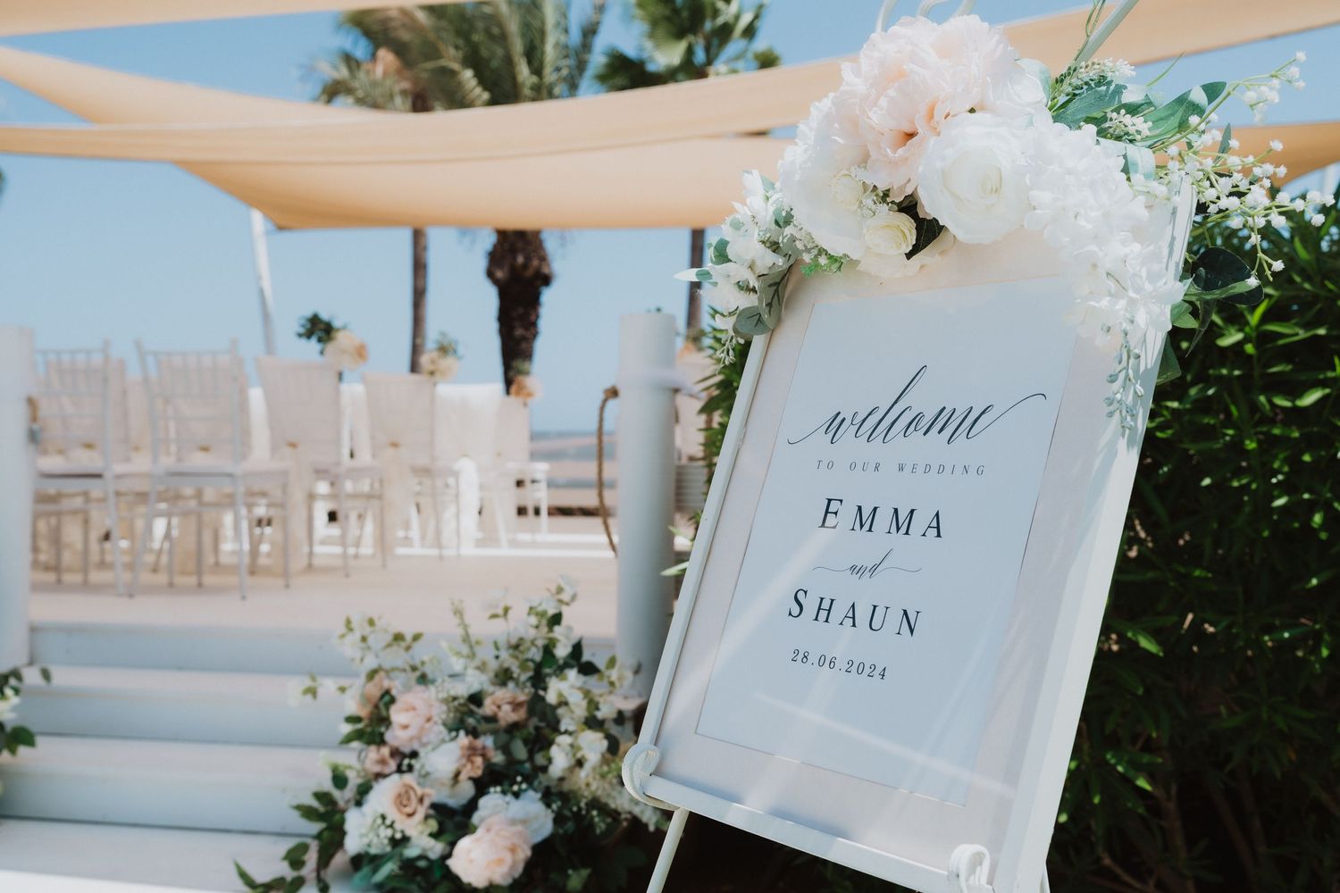 Seaside wedding ceremony space with elegant white decor and floral arrangements.