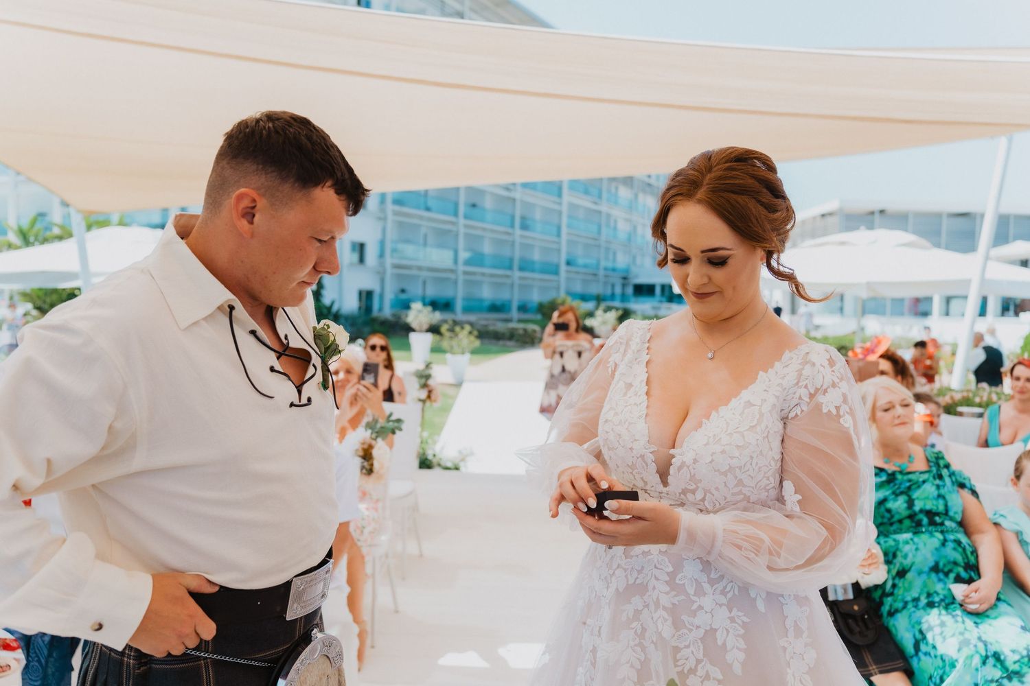 A couple laughs together during their wedding ring exchange at a beachside ceremony.