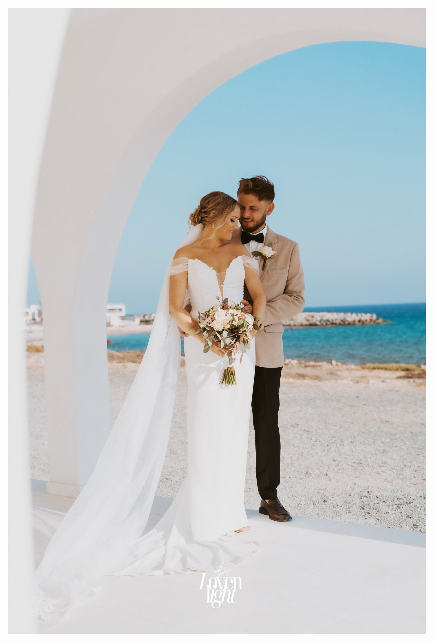 Beautiful coastal wedding photo with Mediterranean architecture and blue ocean views.