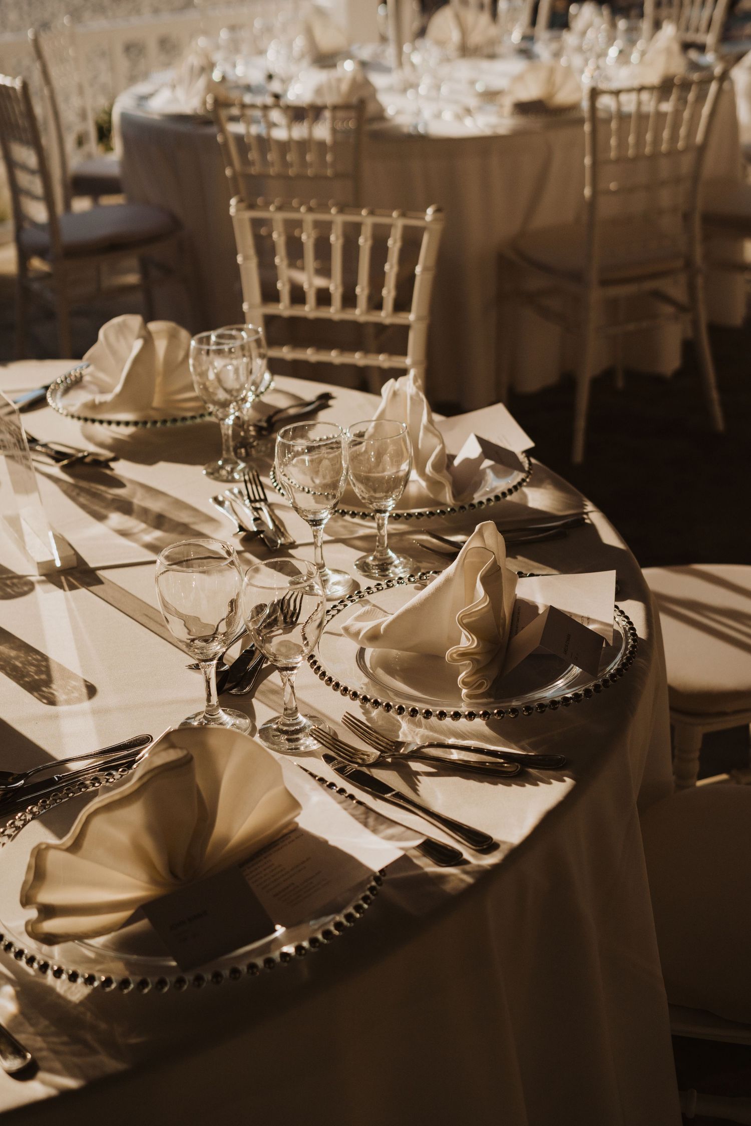 Detailed view of elegant wedding table settings with beaded charger plates in warm sepia tones.