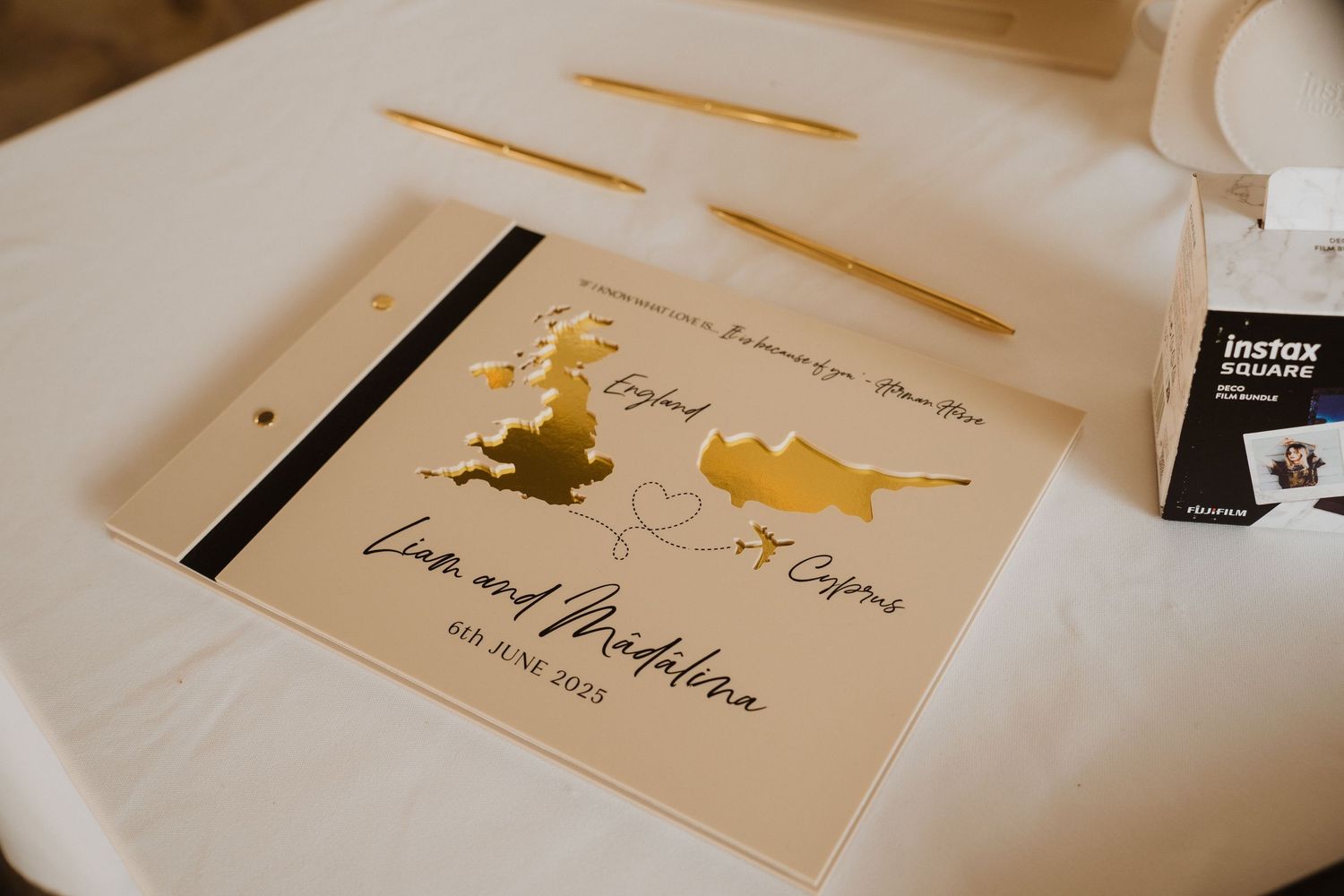 Wedding guest book featuring gold foil maps of England and Cyprus with the couple's names and June 2023 date.