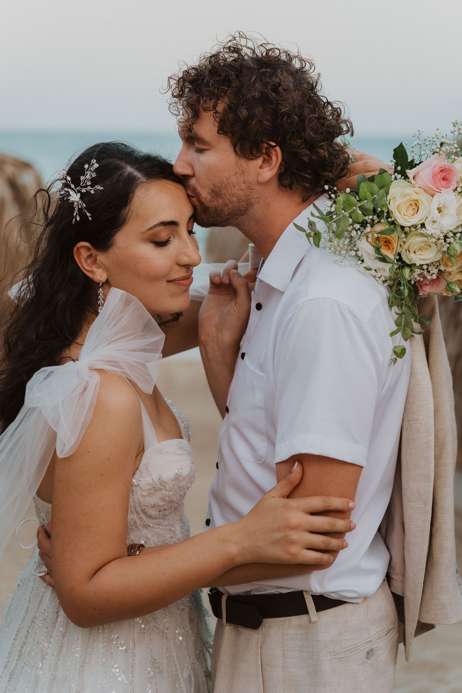 An intimate wedding moment captured on a tropical beach with soft lighting and floral decorations.